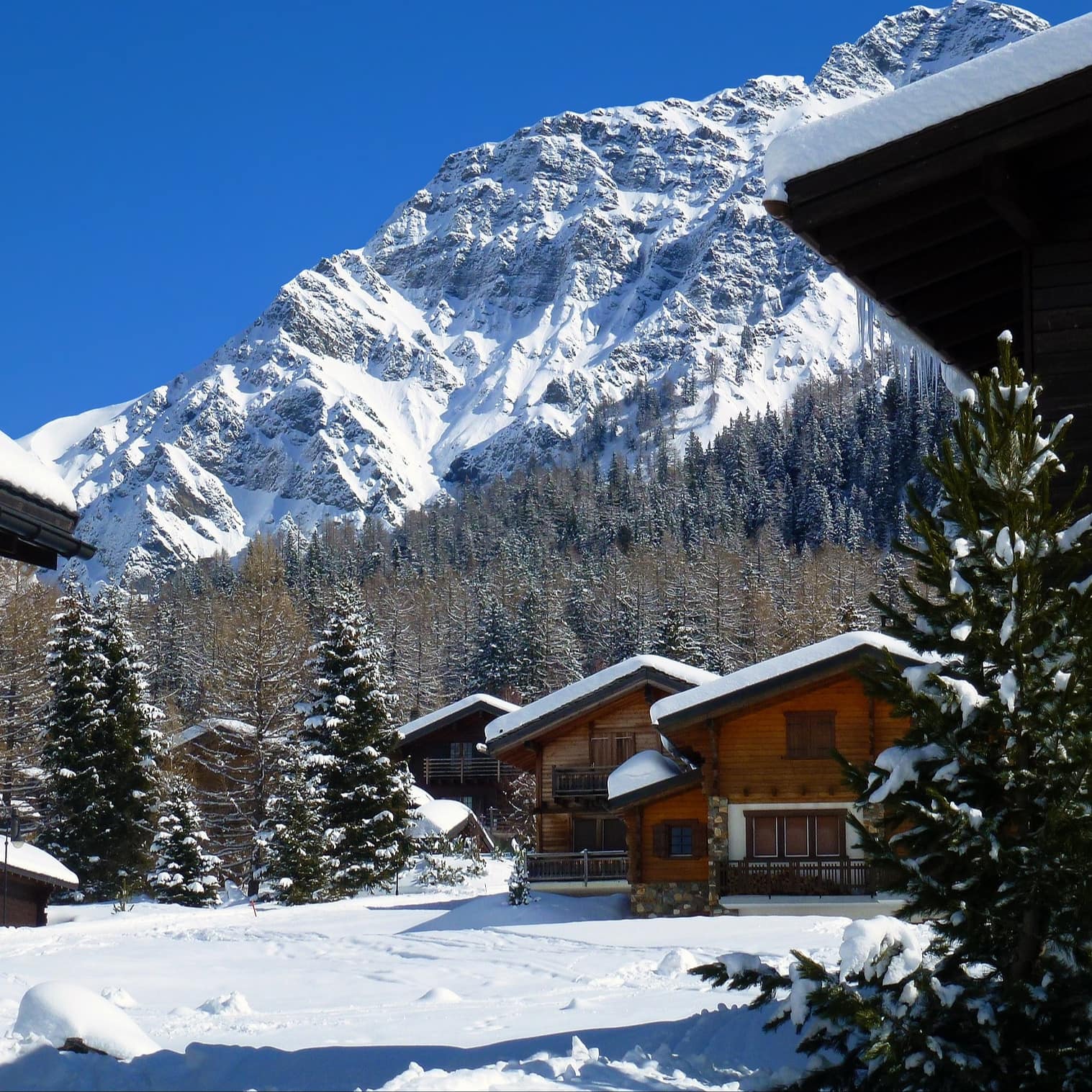 Cozy looking chalets covered in snow with a mountain in the background