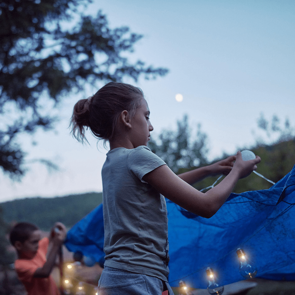 kid building tent, fairy lights, camp at home