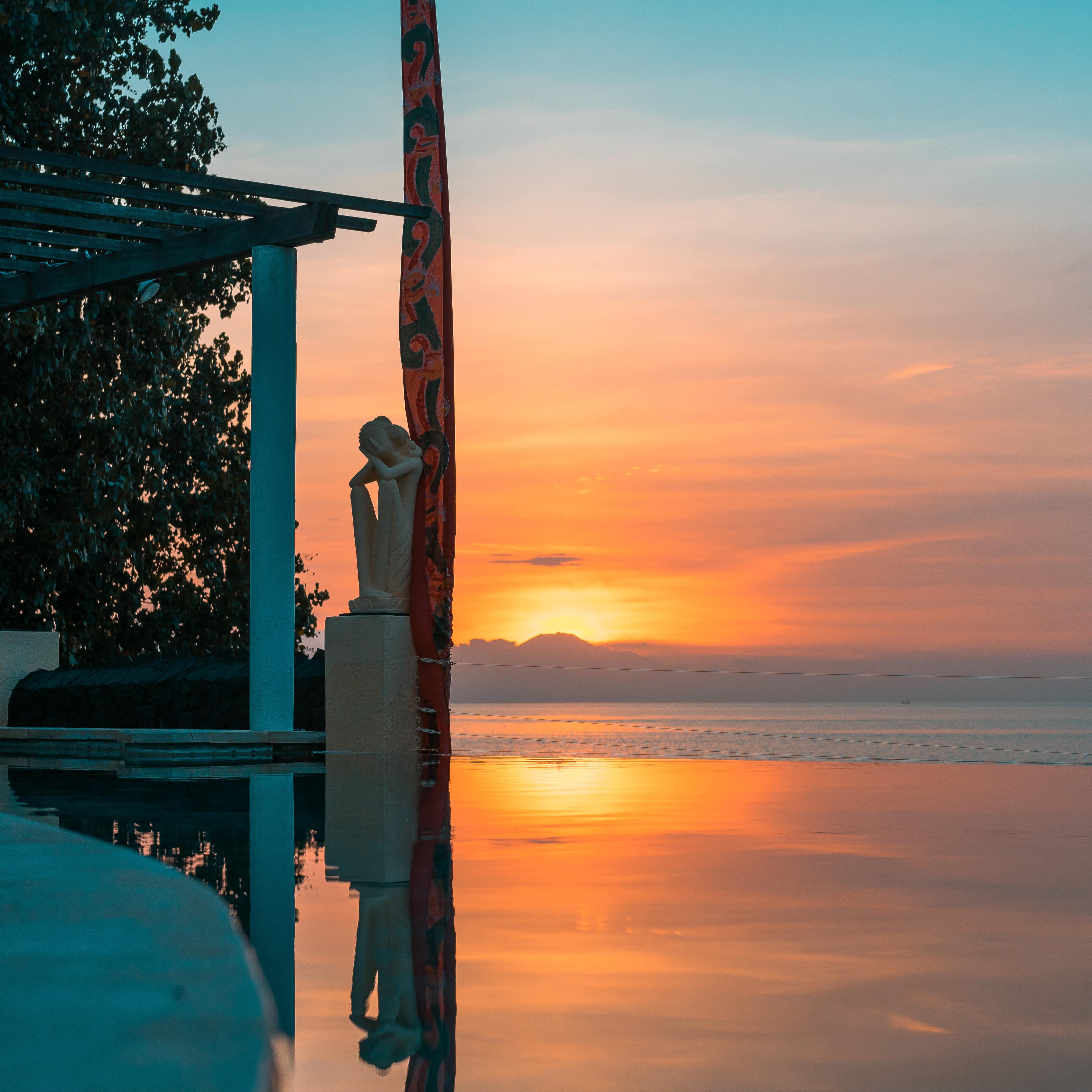 Sunset on the beach at a beachfront villa with arbor and statue of a maiden
