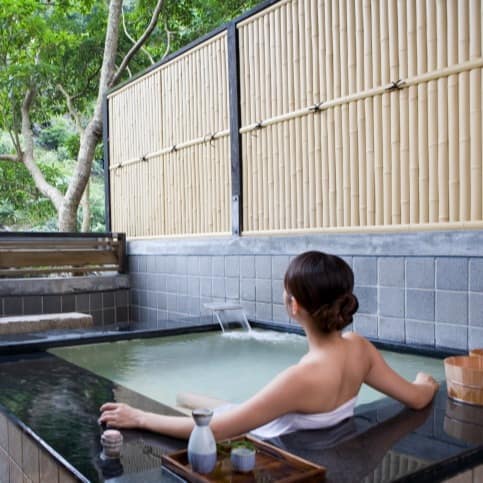 Woman in hot pool looking at the trees in the distance