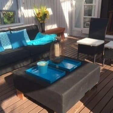 The deck of a family home set with an ottoman surrounded by chairs and couches