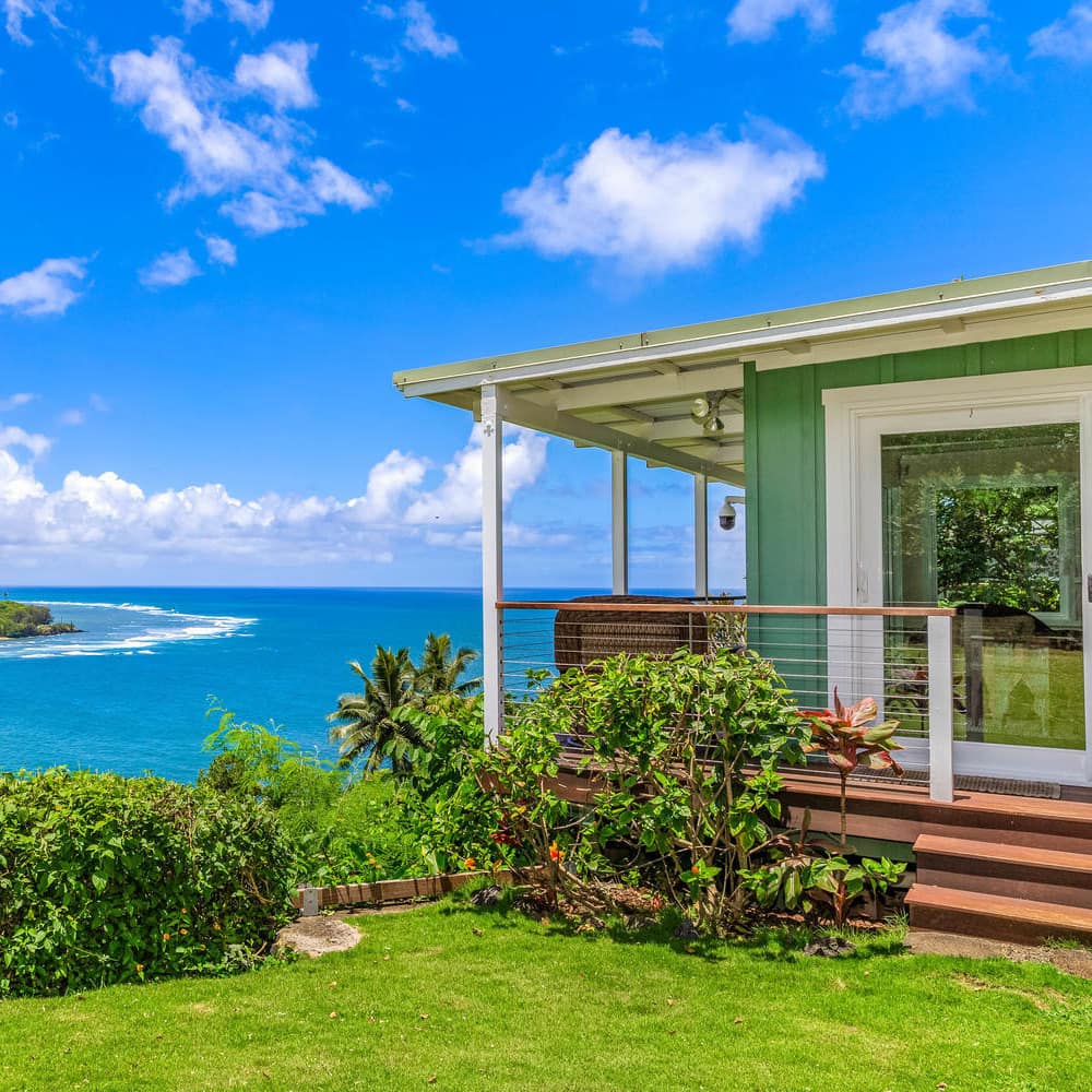 A green-painted shack overlooks an azure bay in Kauai
