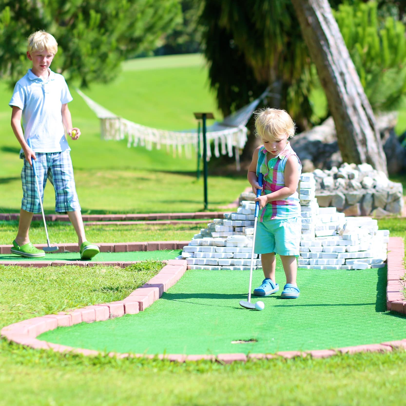 Three children playing mini-golf