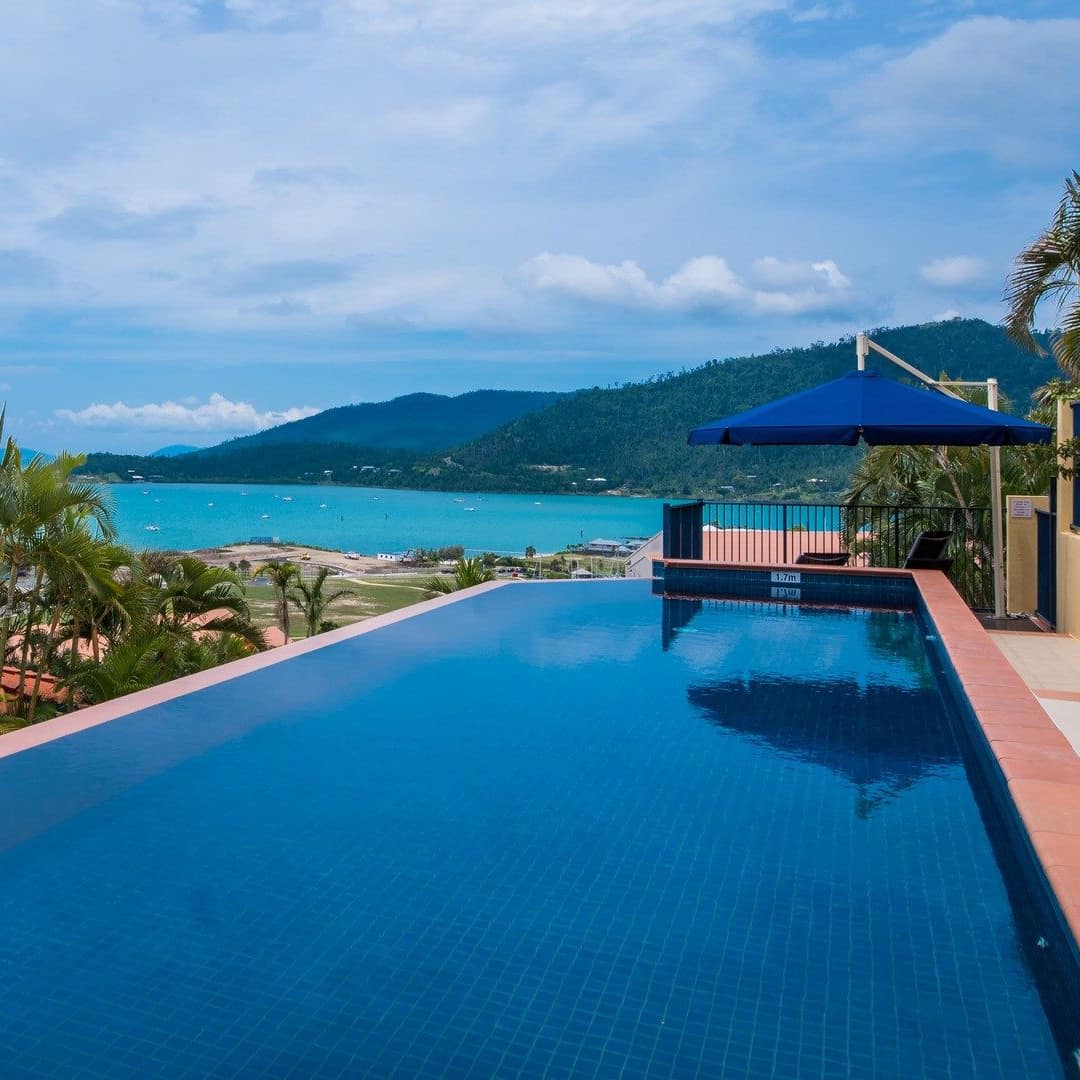 Vanishing edge pool at 3-bedroom Airlie Beach apartment with gorgeous waterfront view and mountains in background