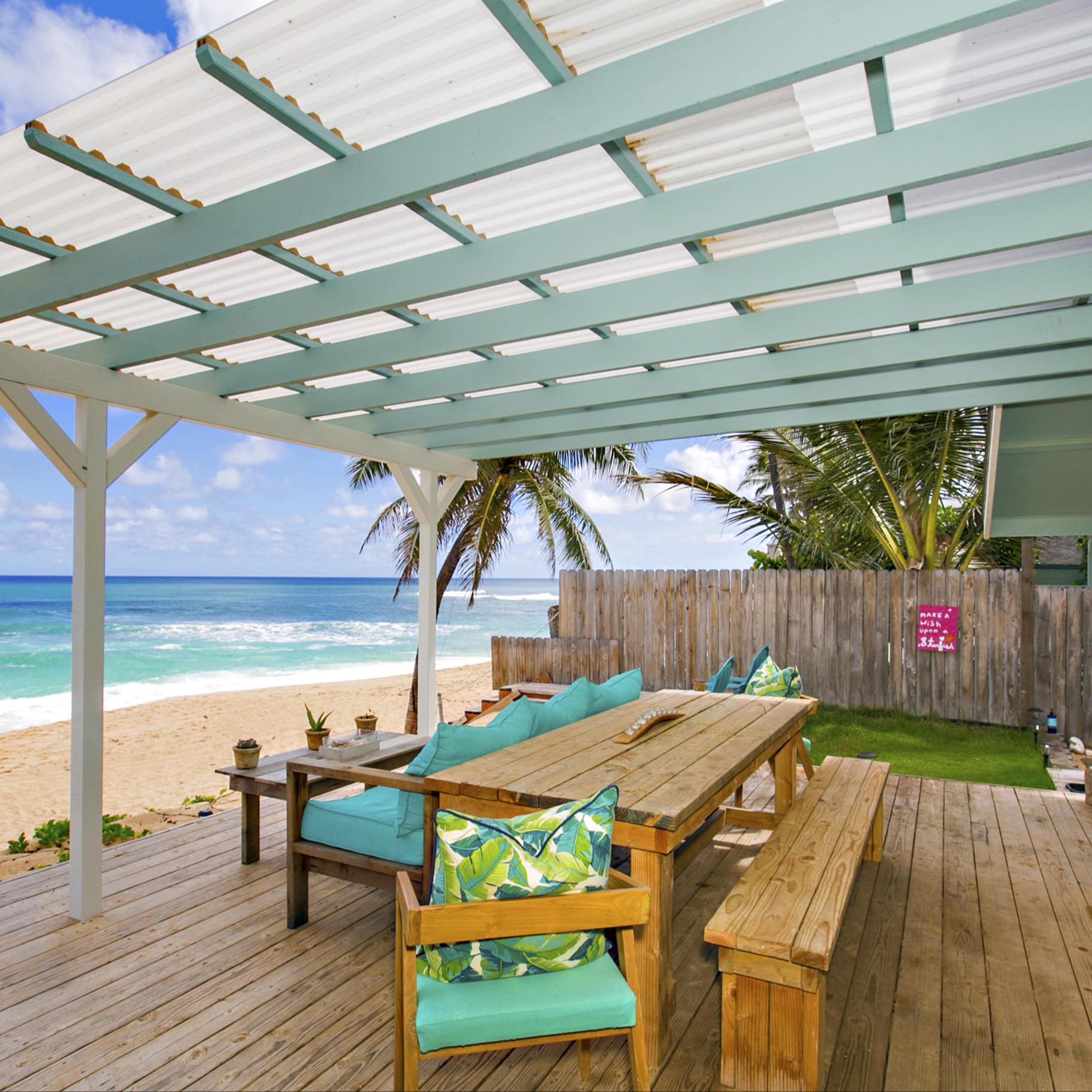 A rental in Oahu opens onto a deck that's just steps from a soft-sand beachfront