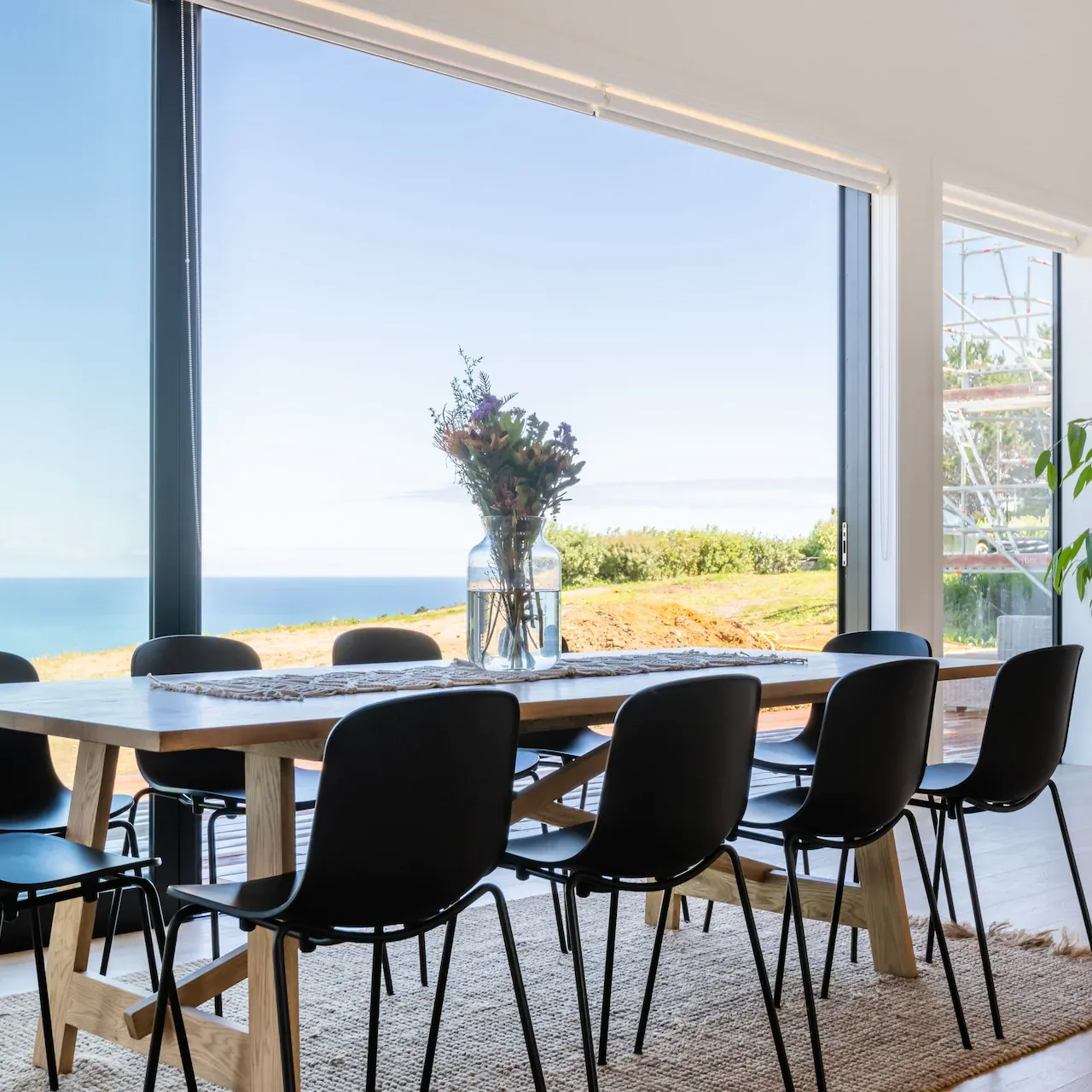 Dining table in a holiday home with a large window-wall looking out over the ocean