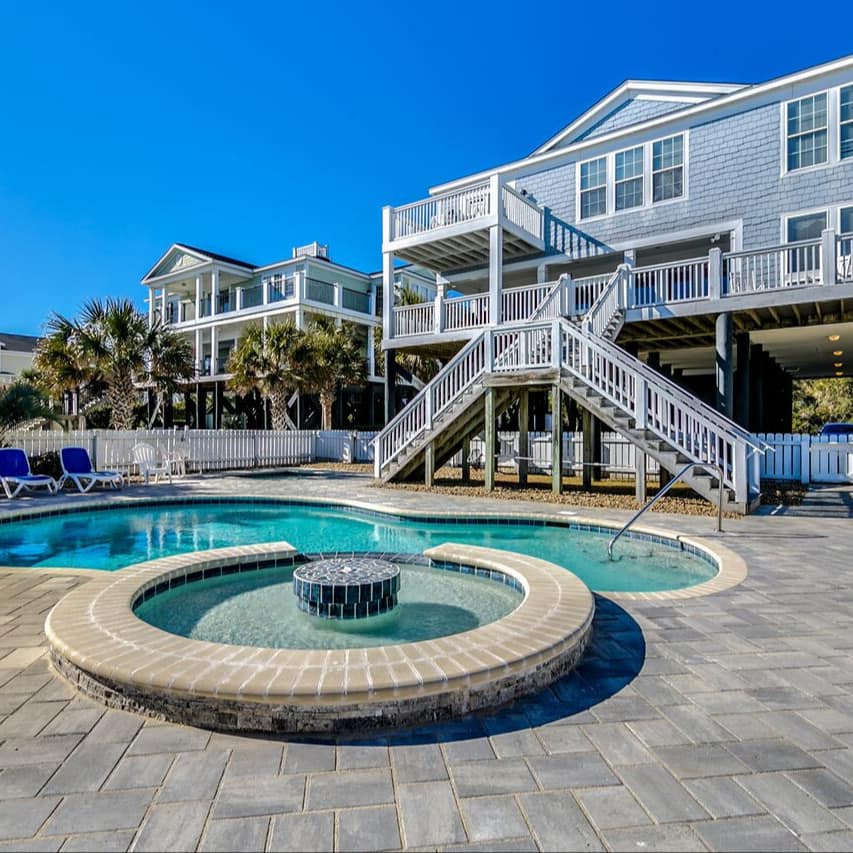 A curvy swimming pool and hot tub are ringed by sunbeds outside a big Myrtle Beach rental