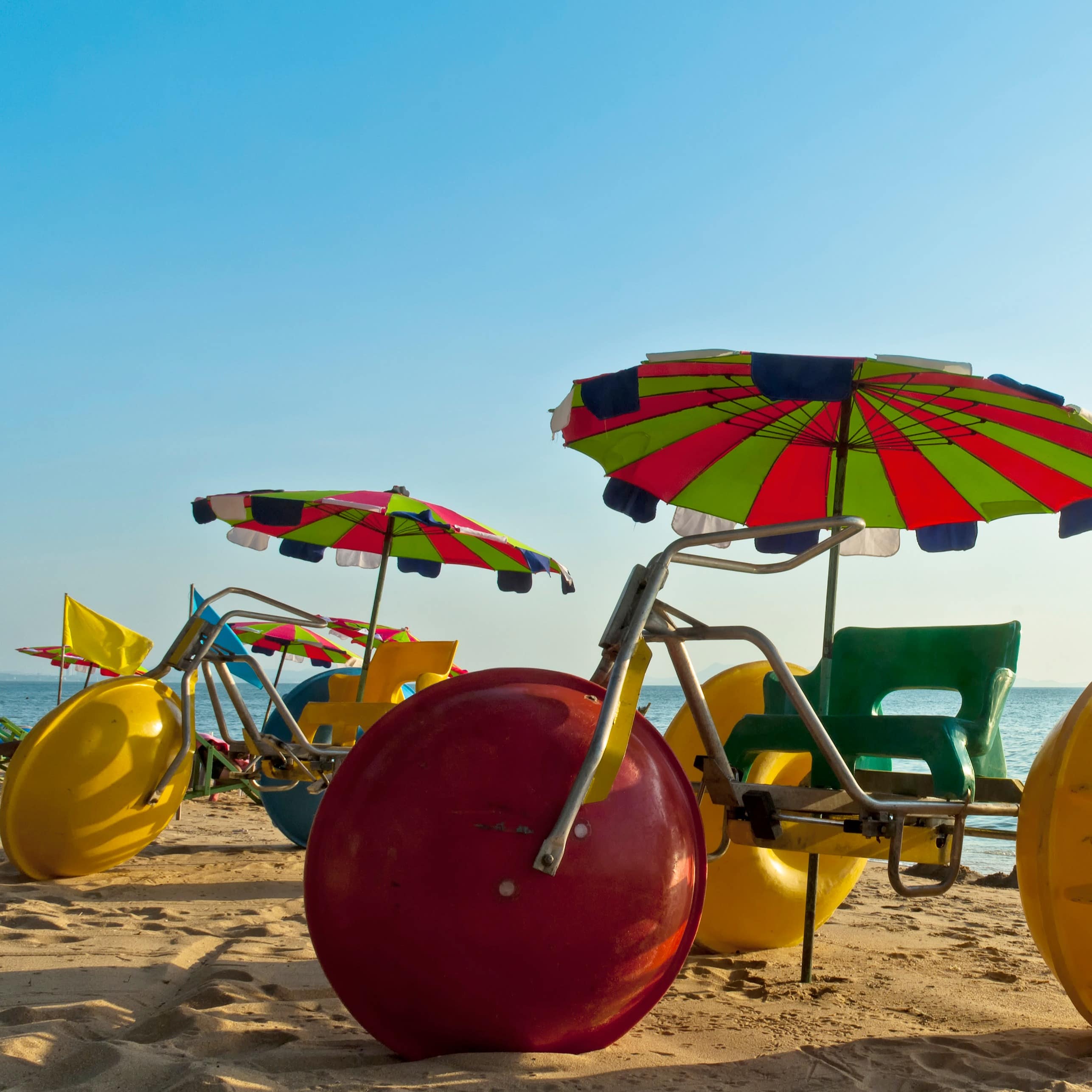 Two colourful water tricycles on the shores of Pattaya Beach