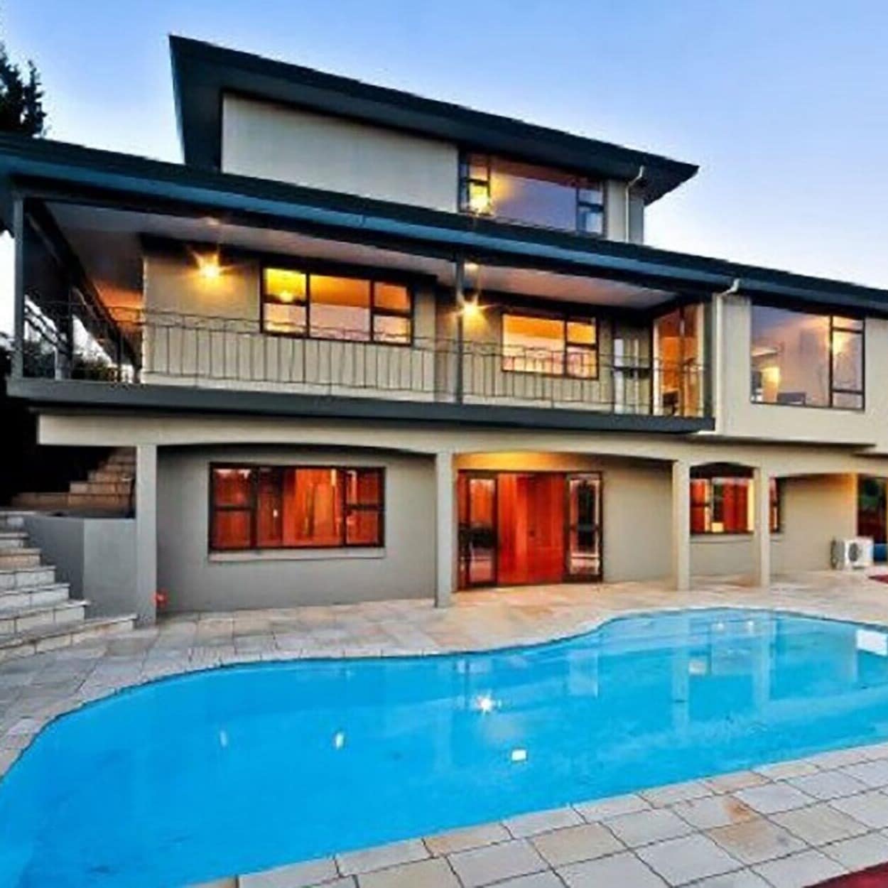 View of the outside of the luxurious Riverlea house with a swimming pool in front