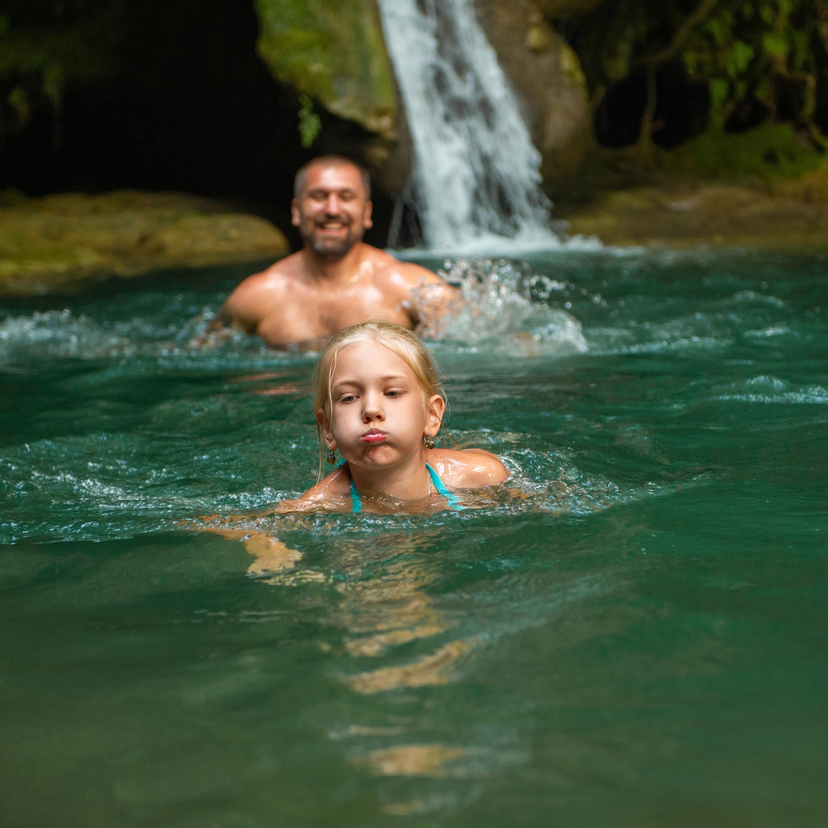 Father and daughter at a waterfall in the jungle