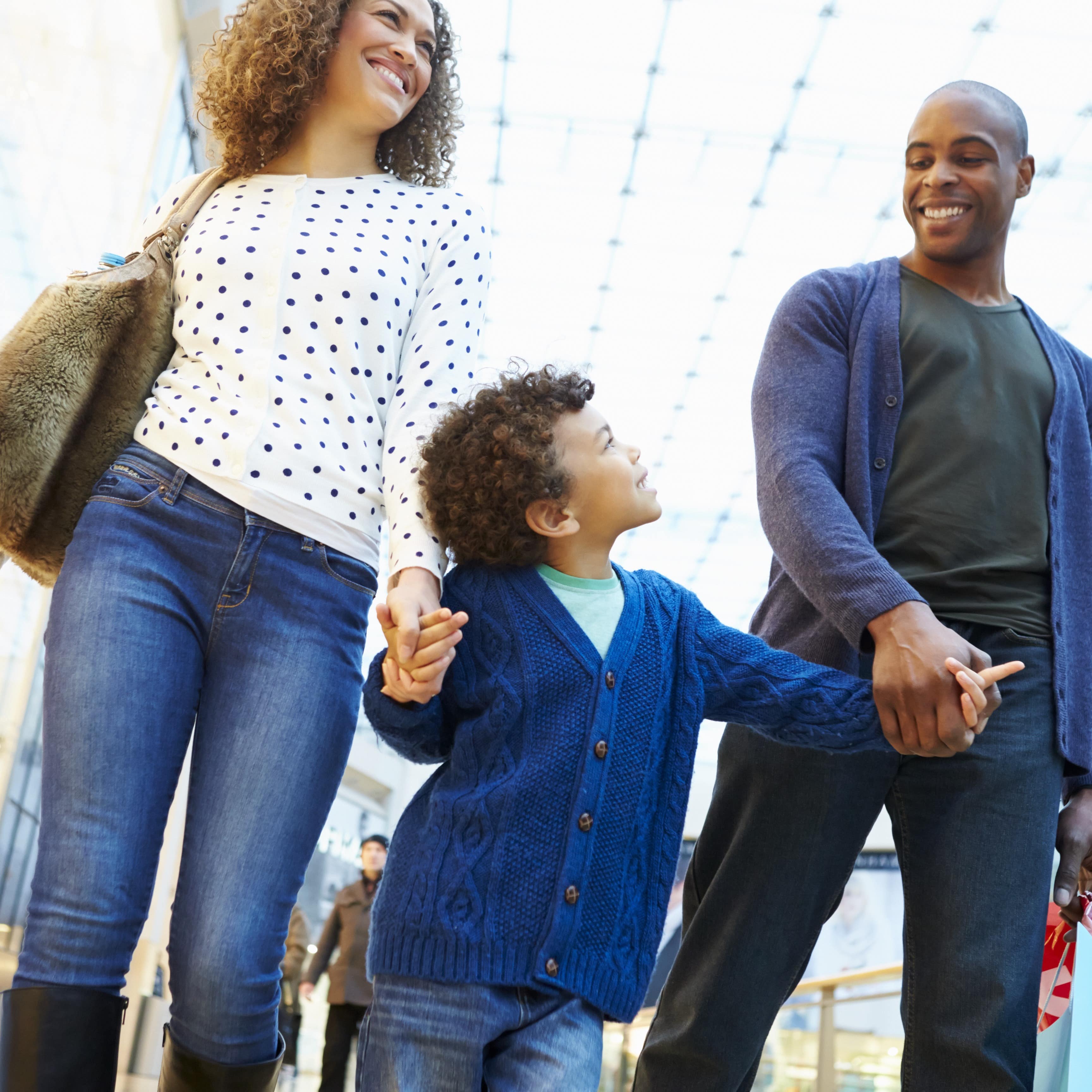 Child holding hands of his parents in a shopping mall
