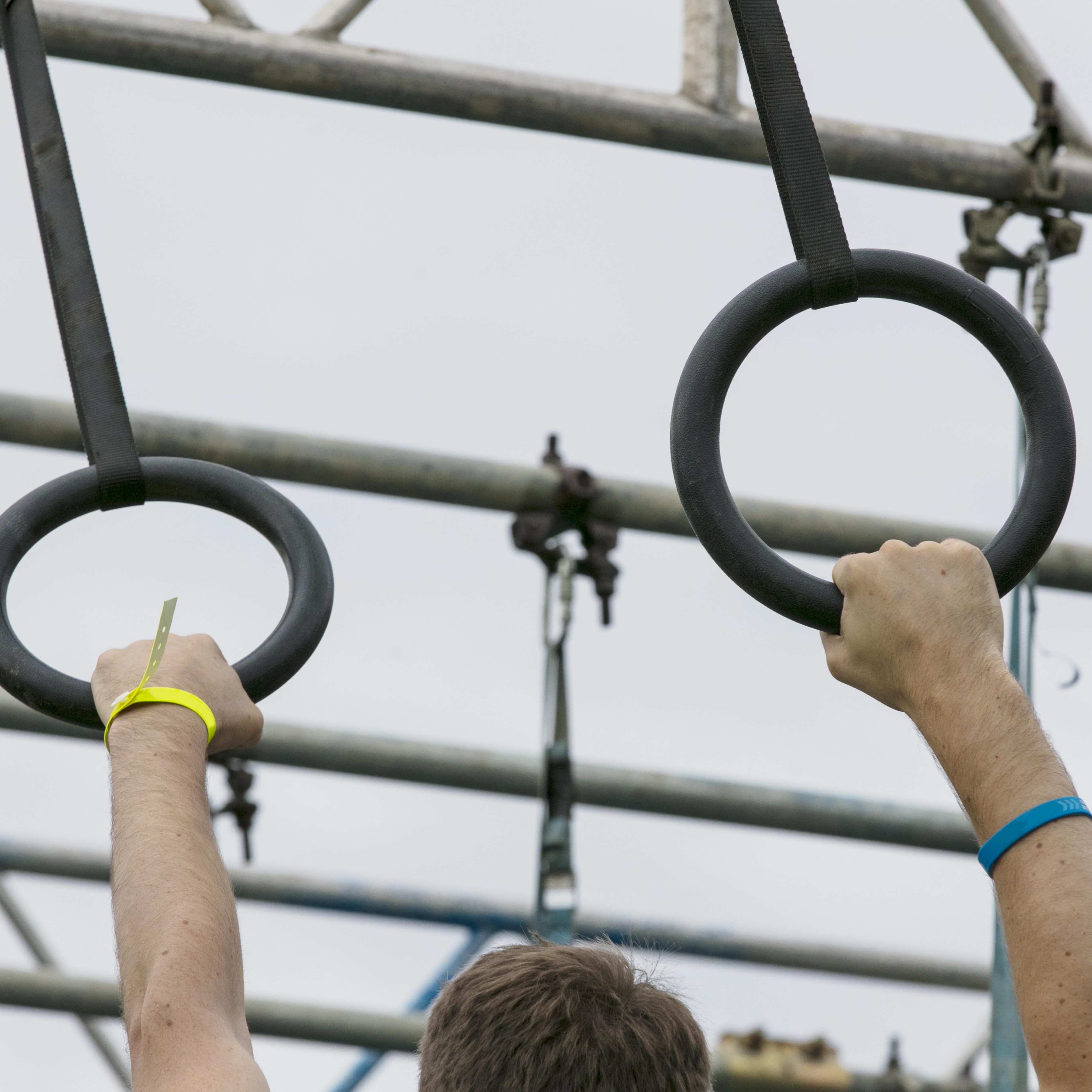 A person hanging on rings of an obstacle course