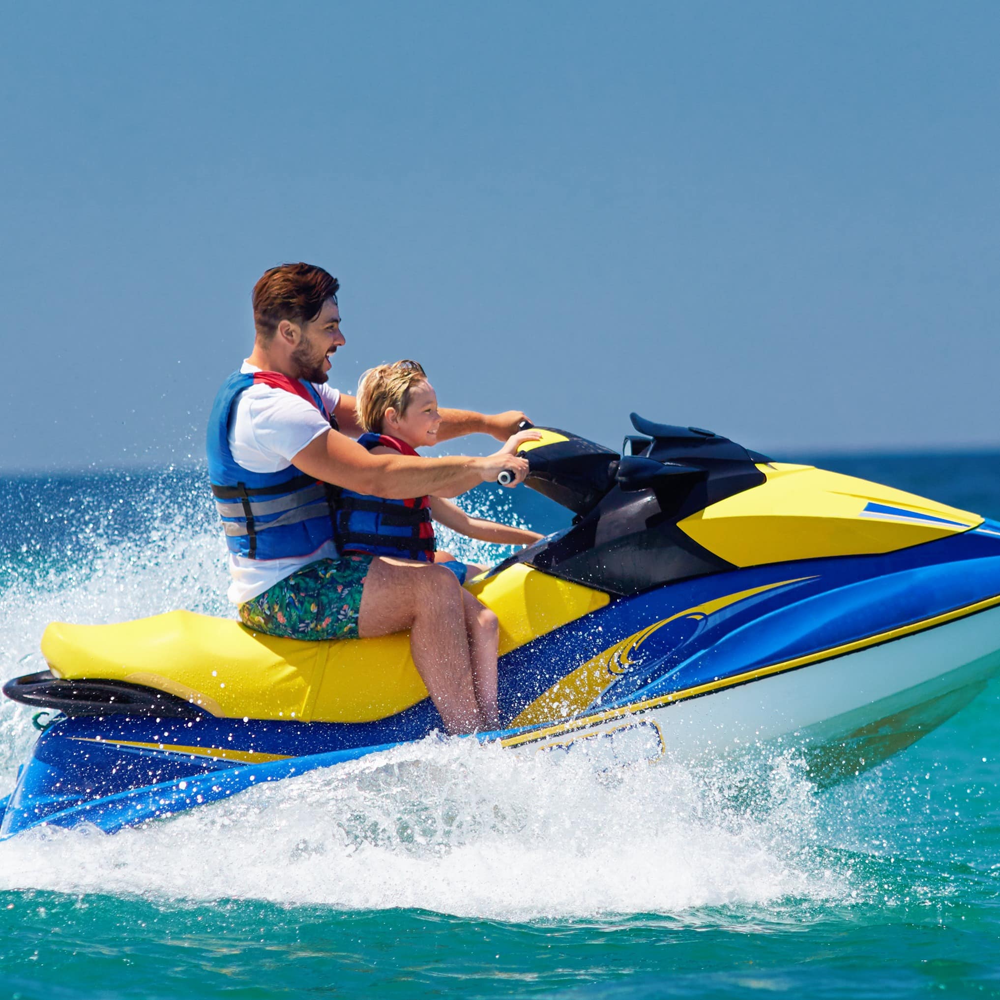 Father and son having fun on jet ski out in ocean