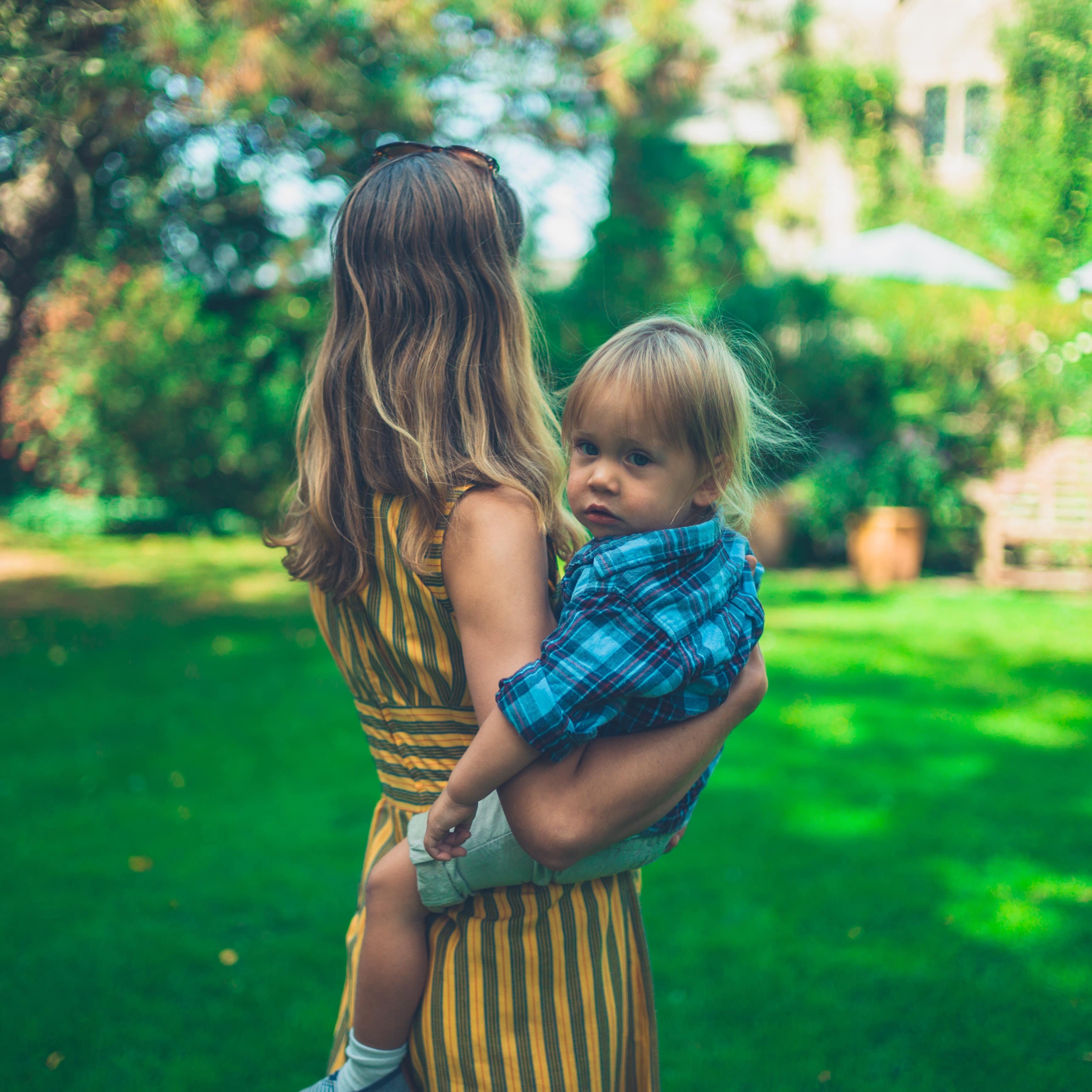 Mother holding a toddler in a lush garden