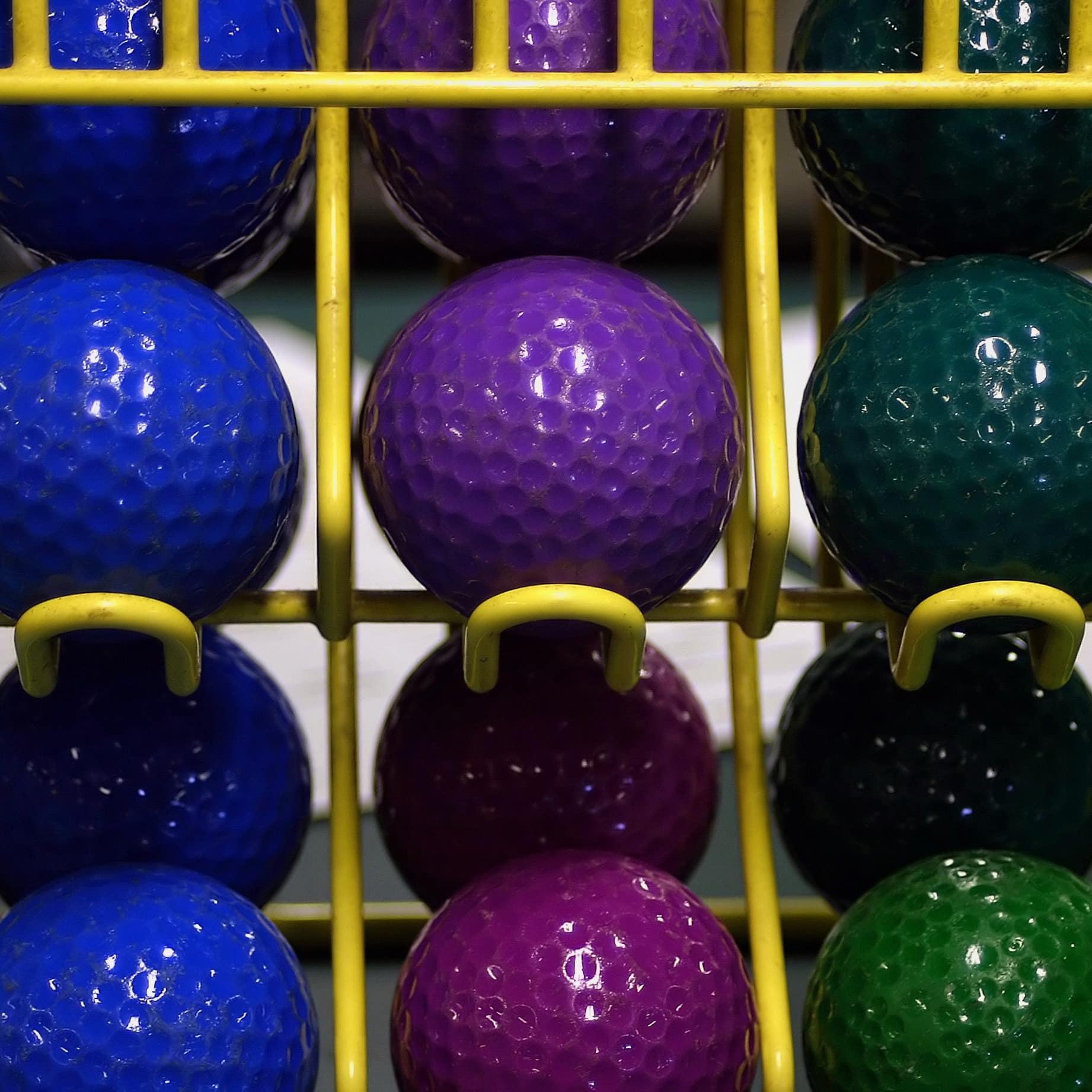 Blue, purple, green mini-golf balls in the rack