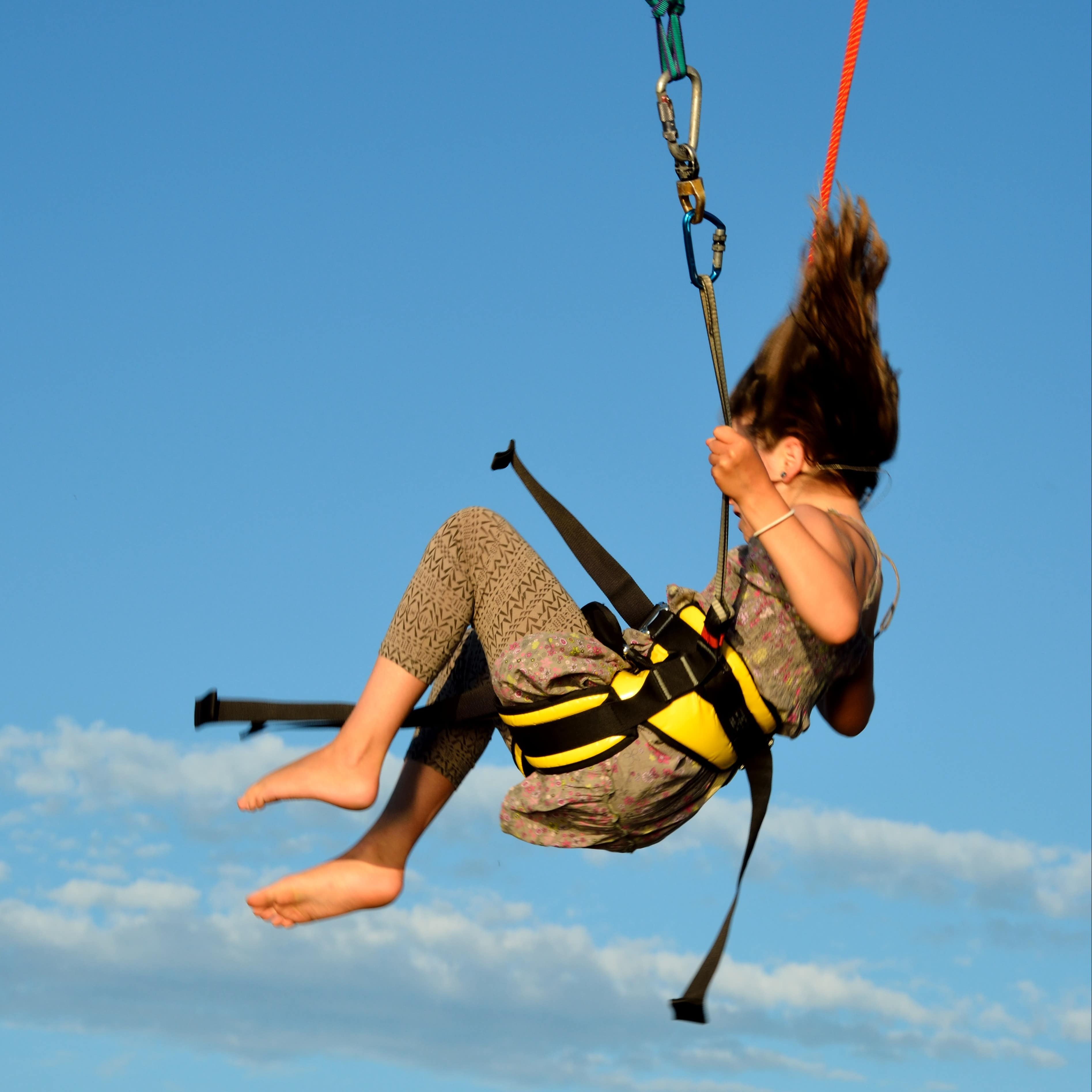 Teen in mid-air after bungy jump with her hair standing straight up