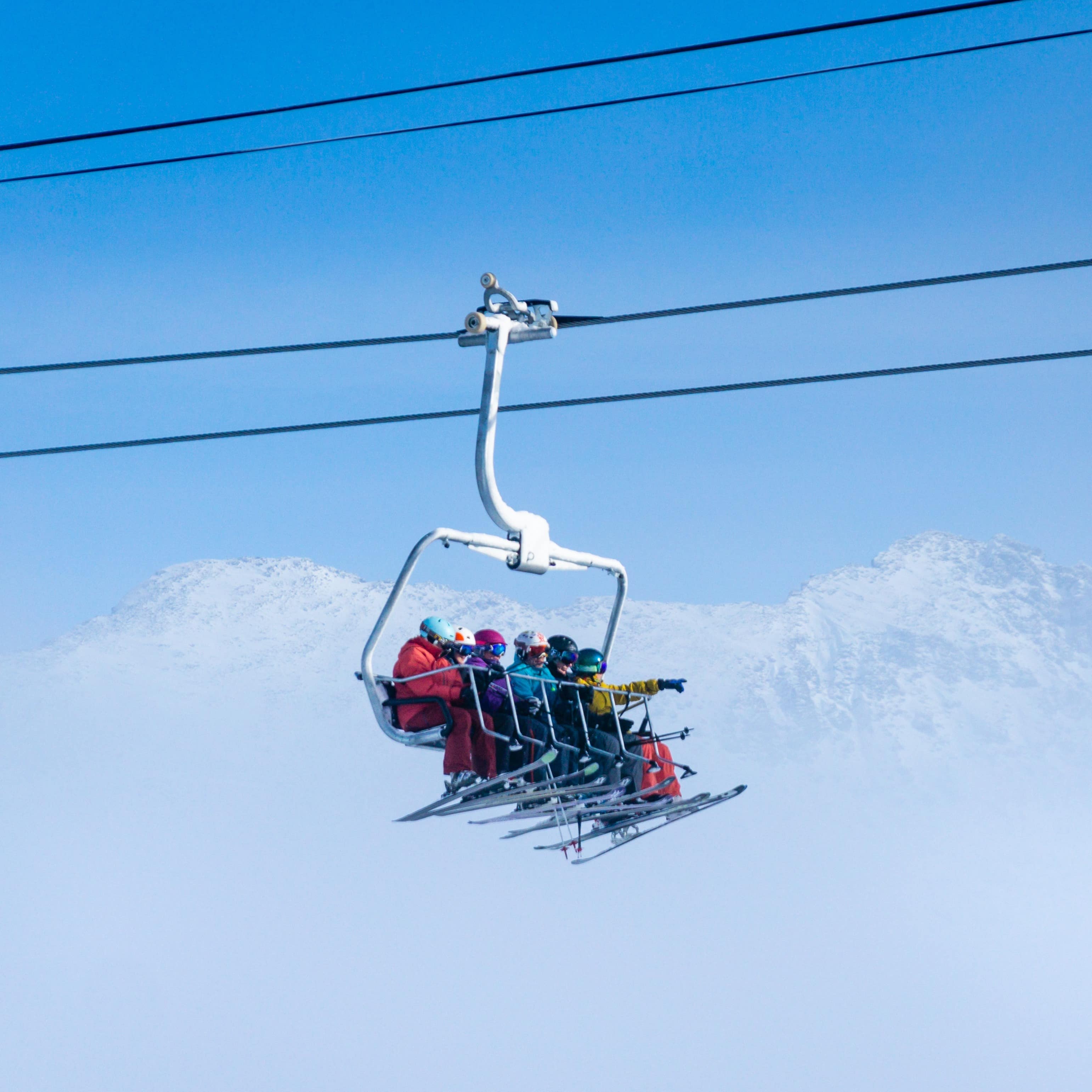 Family of five on a ski lift with mountains in the background hidden by clouds