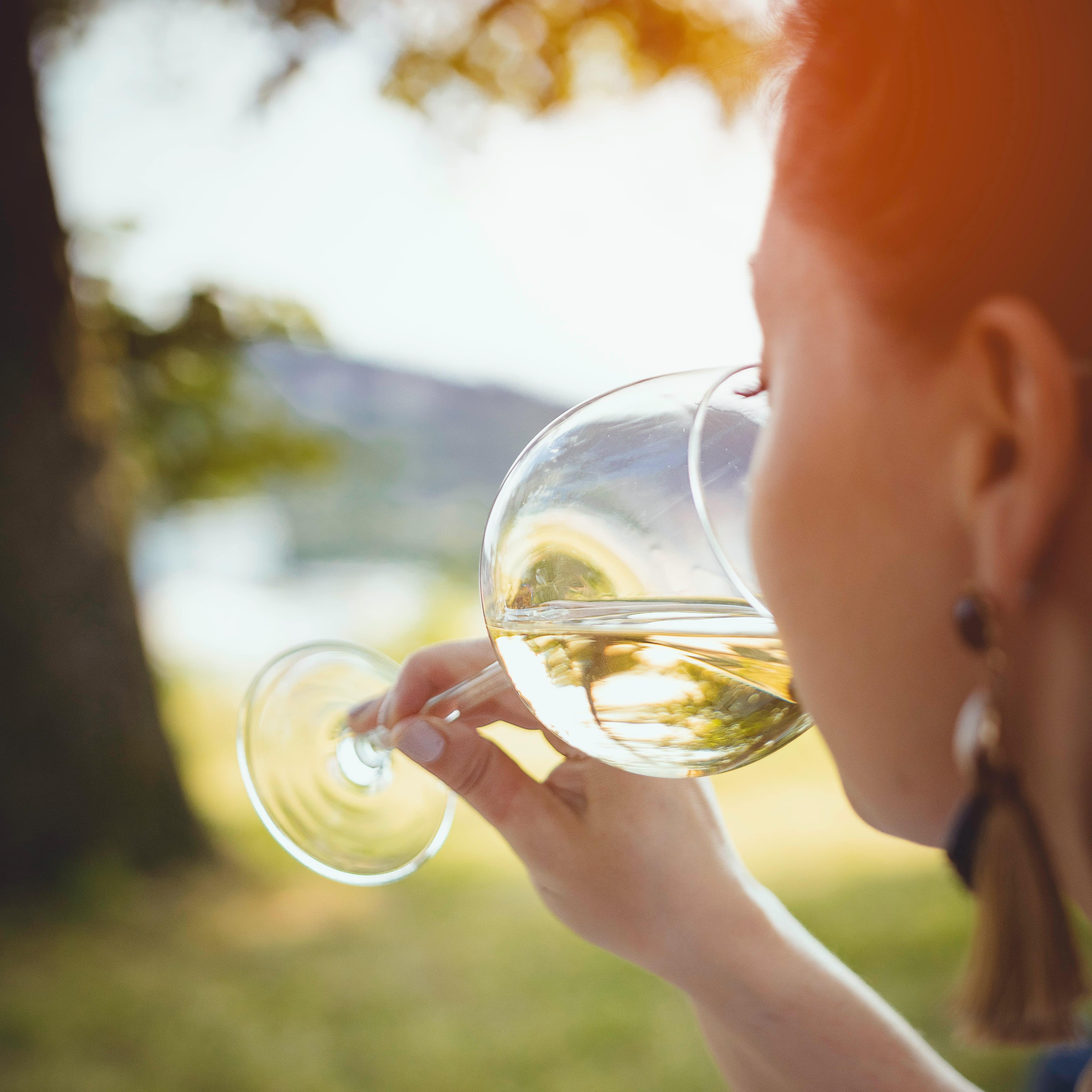 Woman drinking a glass of white wine in the sunshine