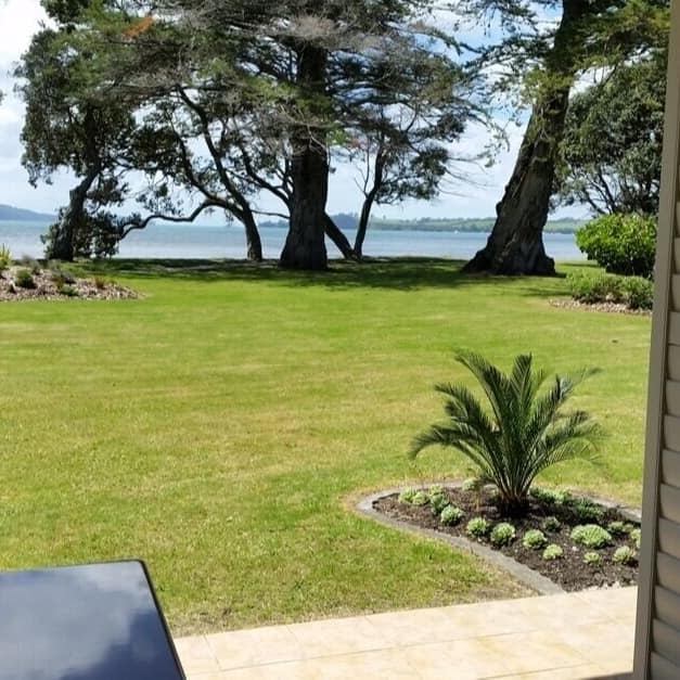 View from the window of a rental property in Matakana looking out at lawn and the water