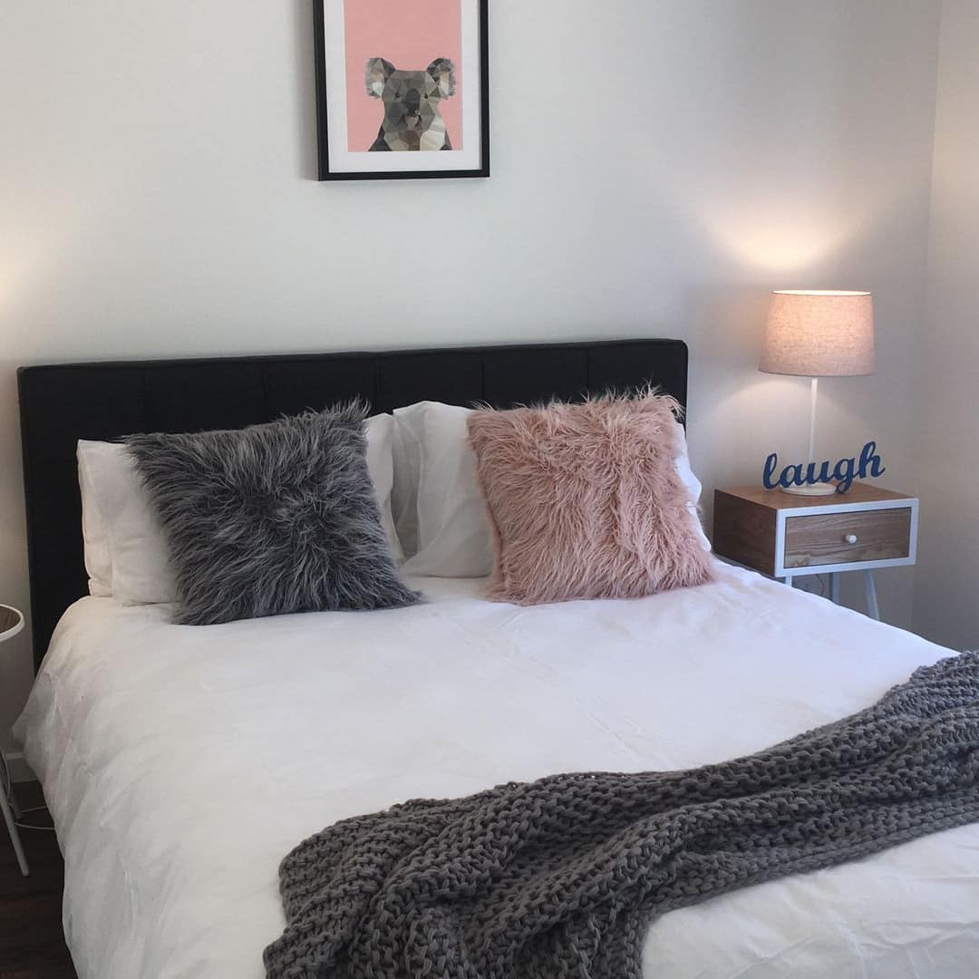 Bedroom with a queen size bed, white bedding, grey and pink decor, wooden bedside tables, koala painting.