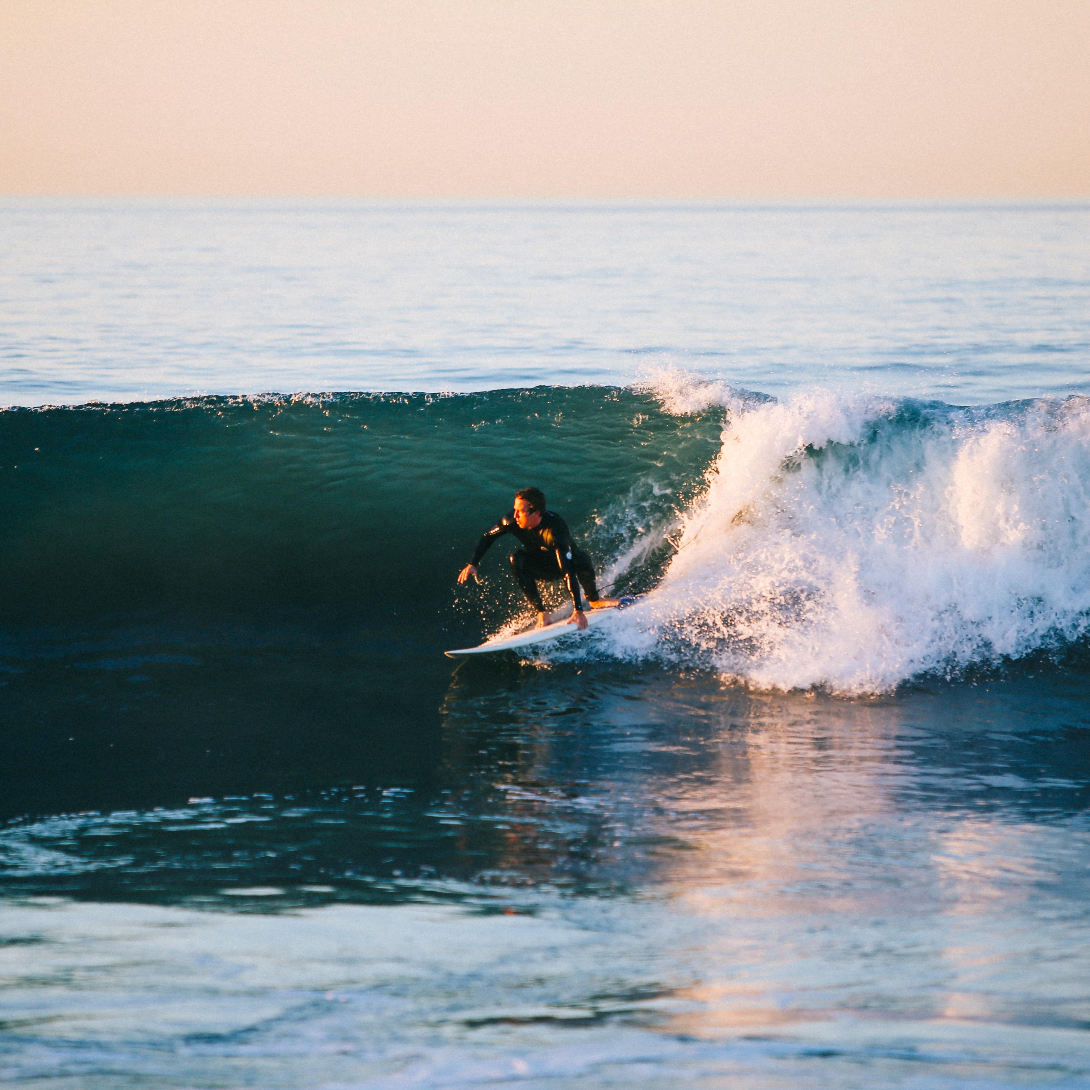 Man surfing on a wave at sunset