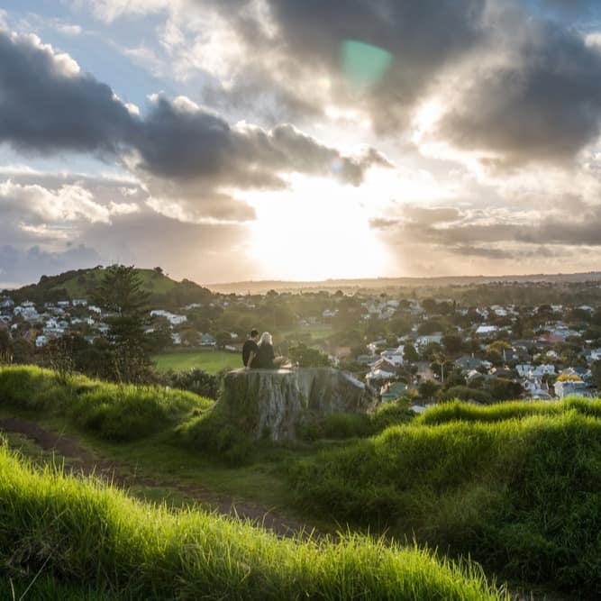 Couple sitting on a tree stump overlooking the neighbourhoods surrounding Takapuna Beach
