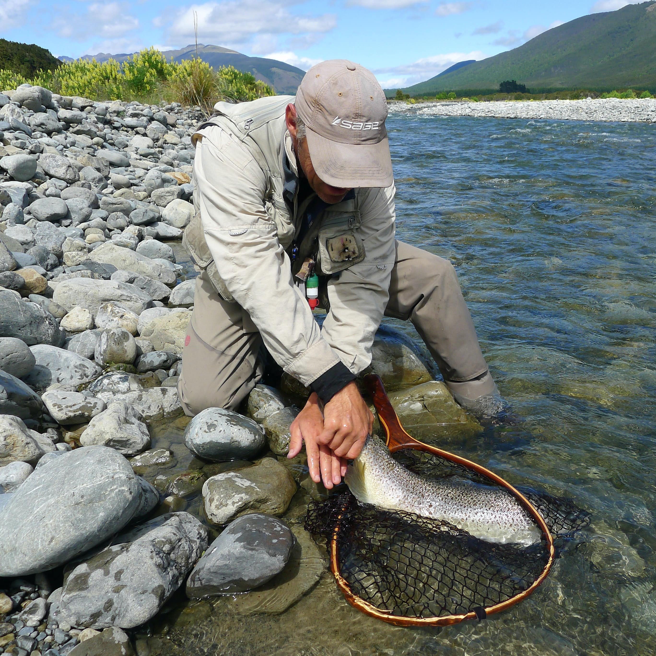 Man holding a trout in a net that he caught in the lake