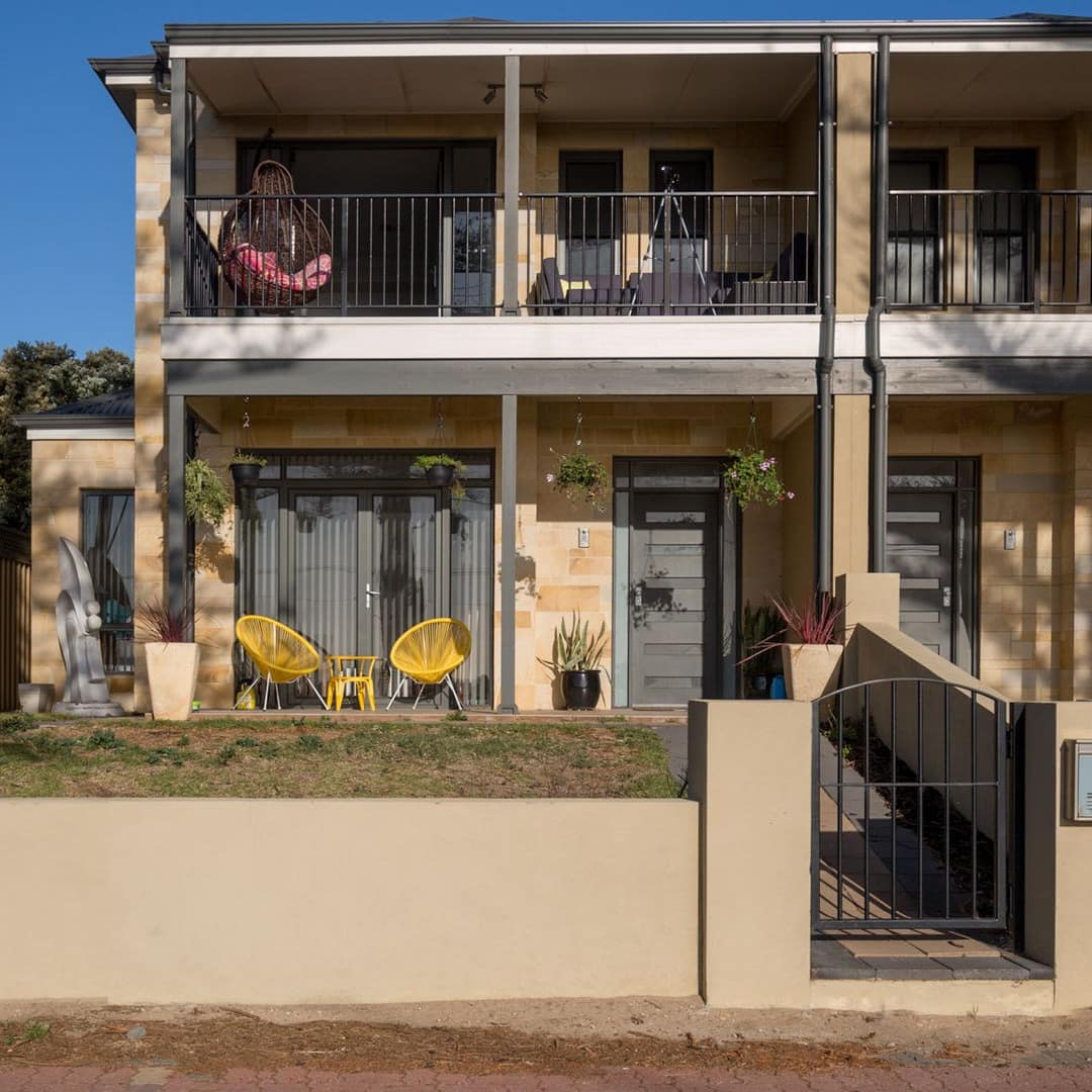 3-bedroom apartment in cream-coloured stone building with front patio and upper floor balconies
