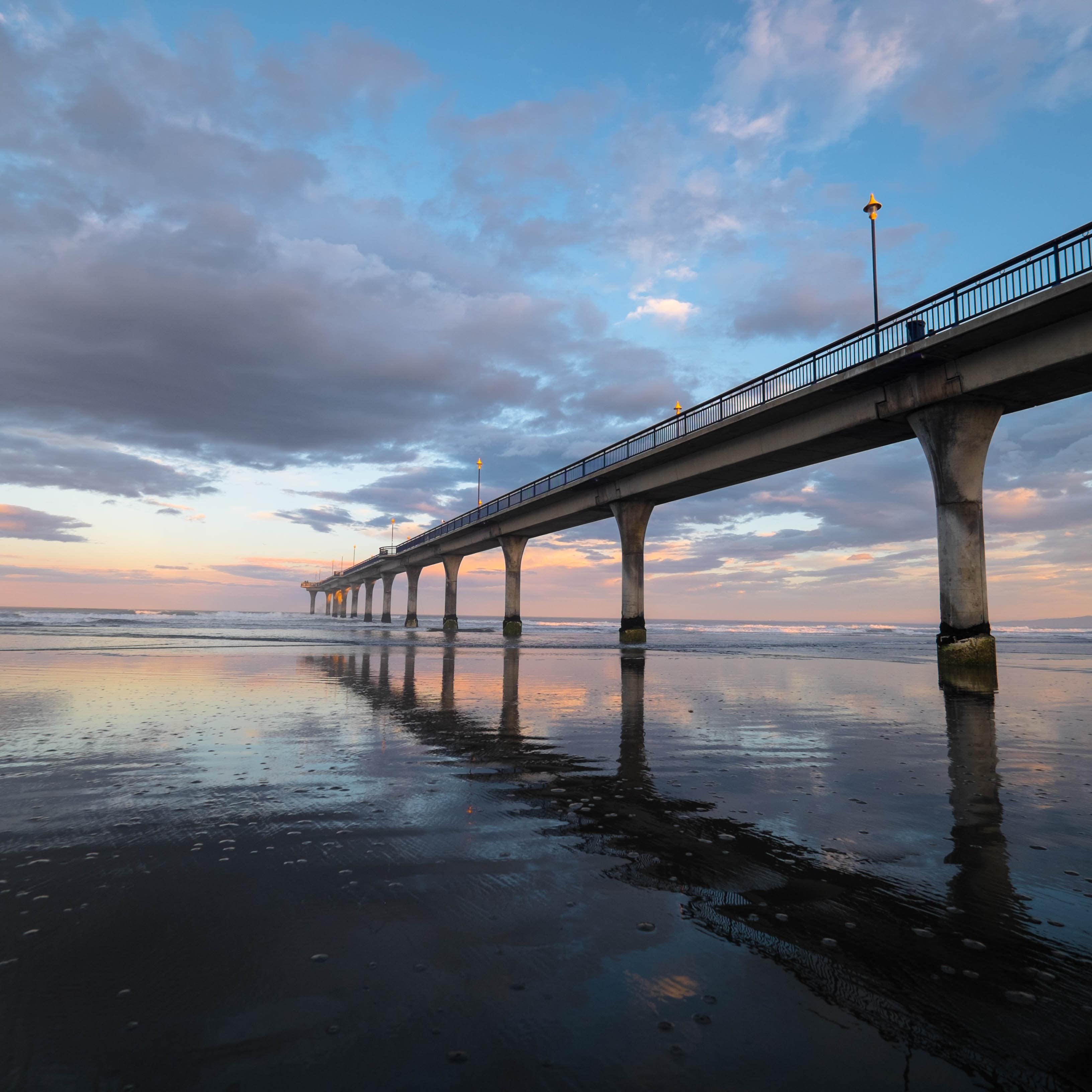 New Brighton Pier and its reflection in the clear water at sunset