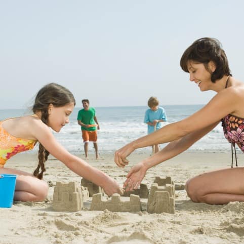 Mother and daughter building a sand castle on the beach