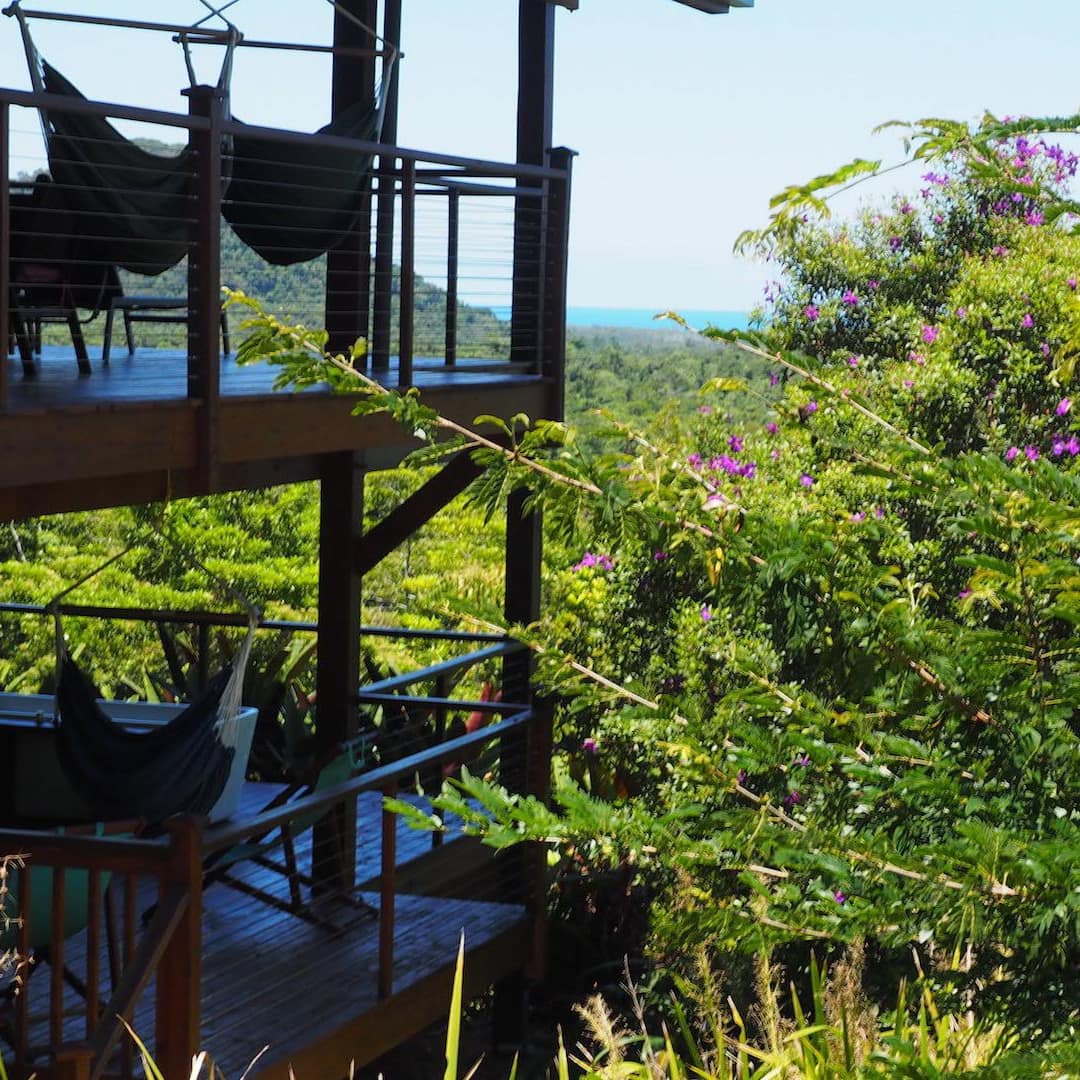 Rainforest house in Cape Tribulation with multiple porches and hammocks surrounded by lush greenery
