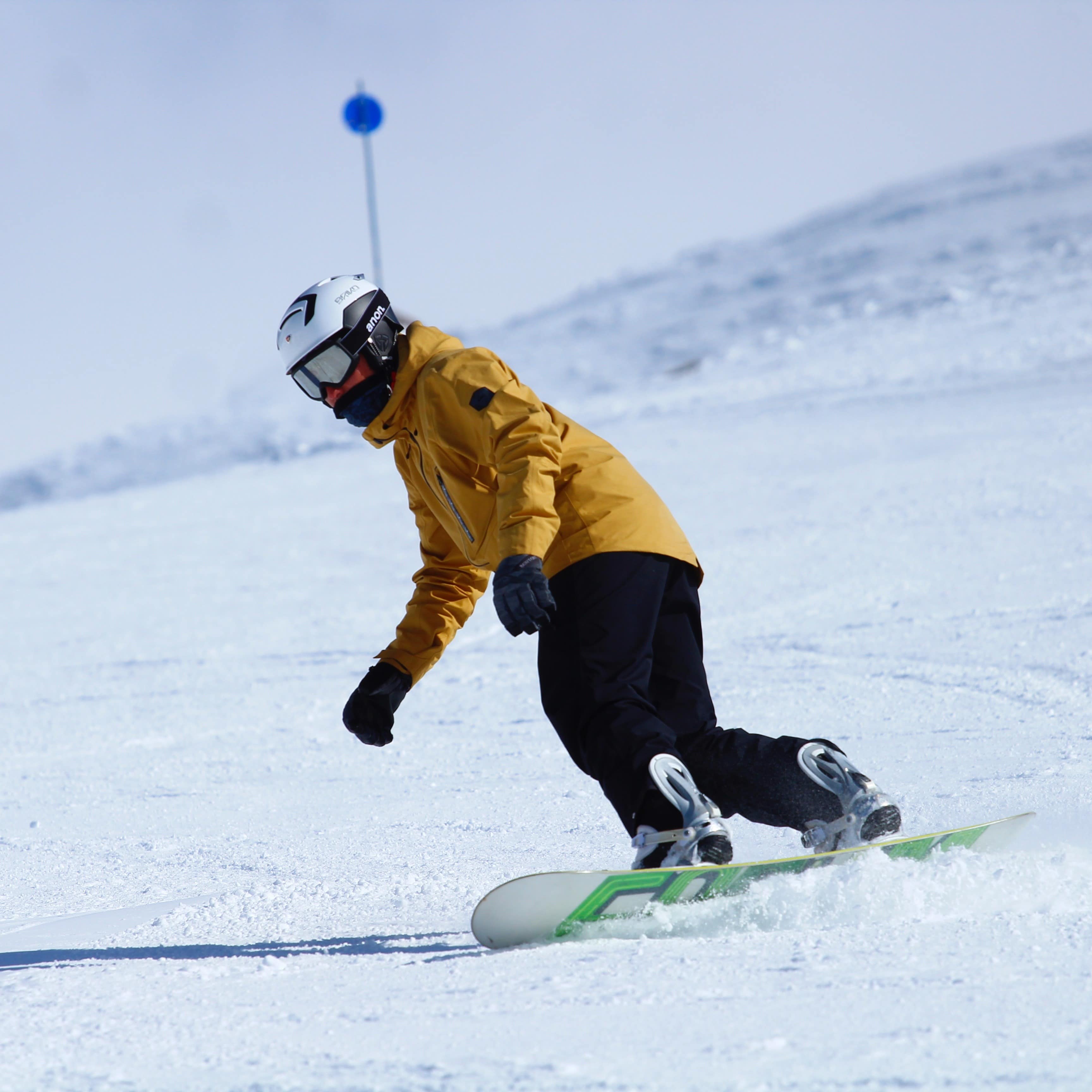 Person in a yellow jacket snowboarding