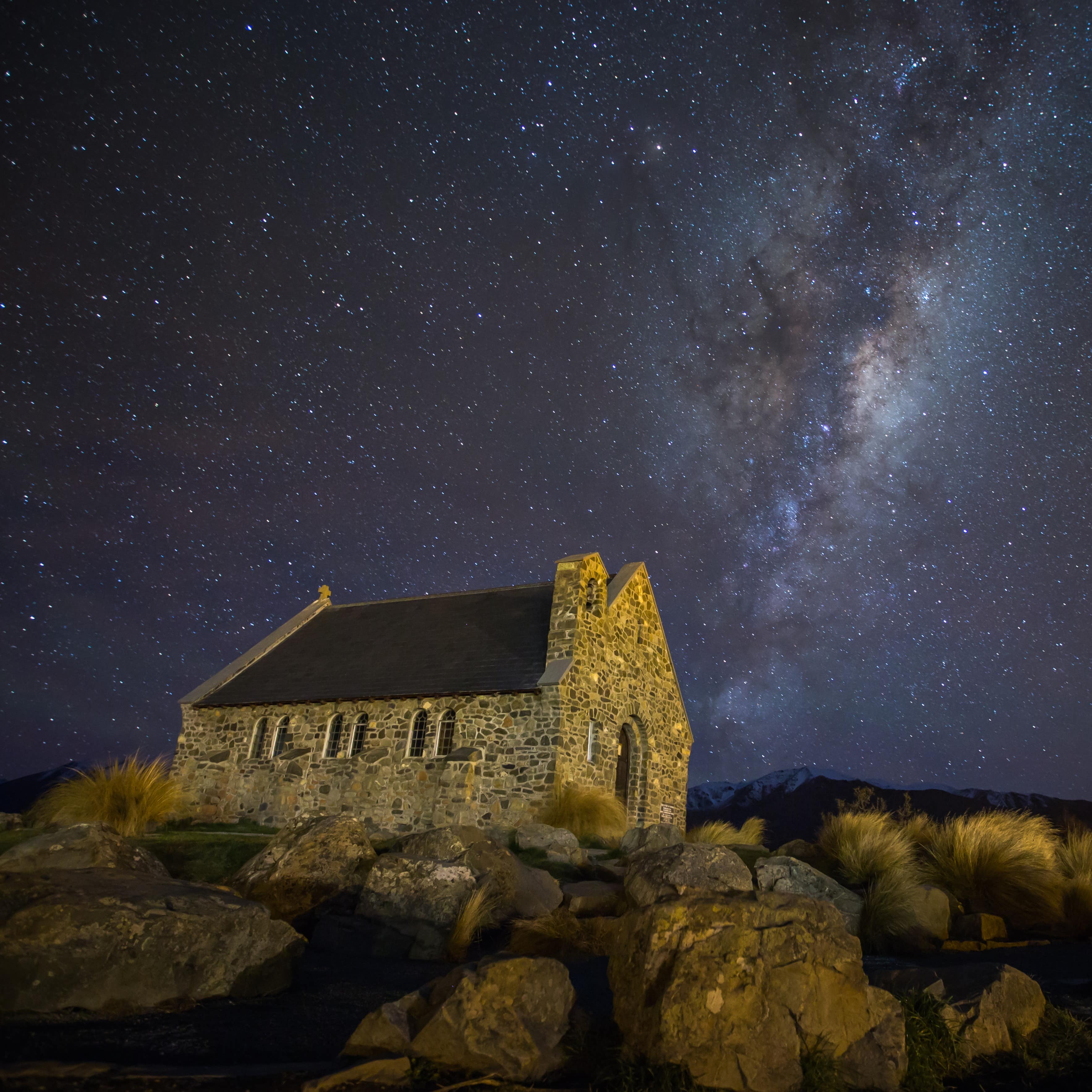 Small brick house on a hill with a clear view of the Milky Way in the night sky