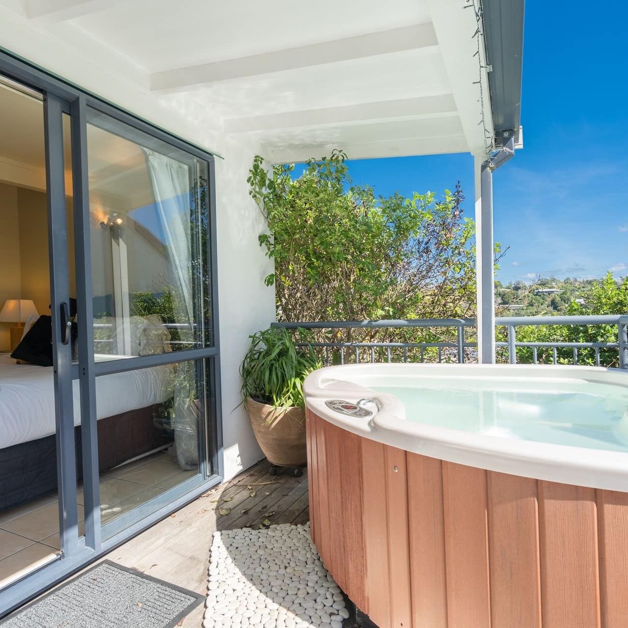Filled hot tub on the balcony outside the sliding glass doors of a bedroom