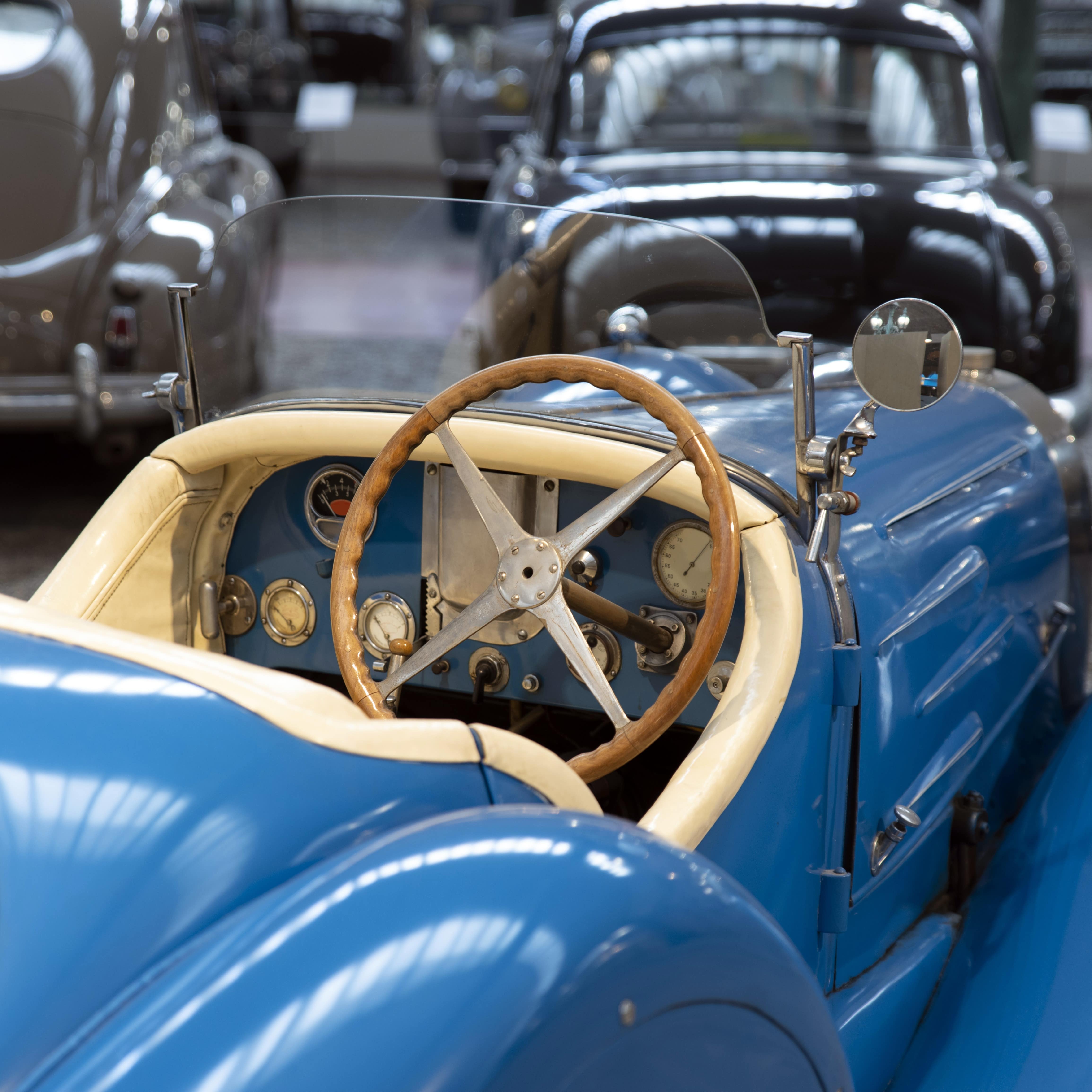 Close up view of a vintage blue convertible with wooden steering wheel