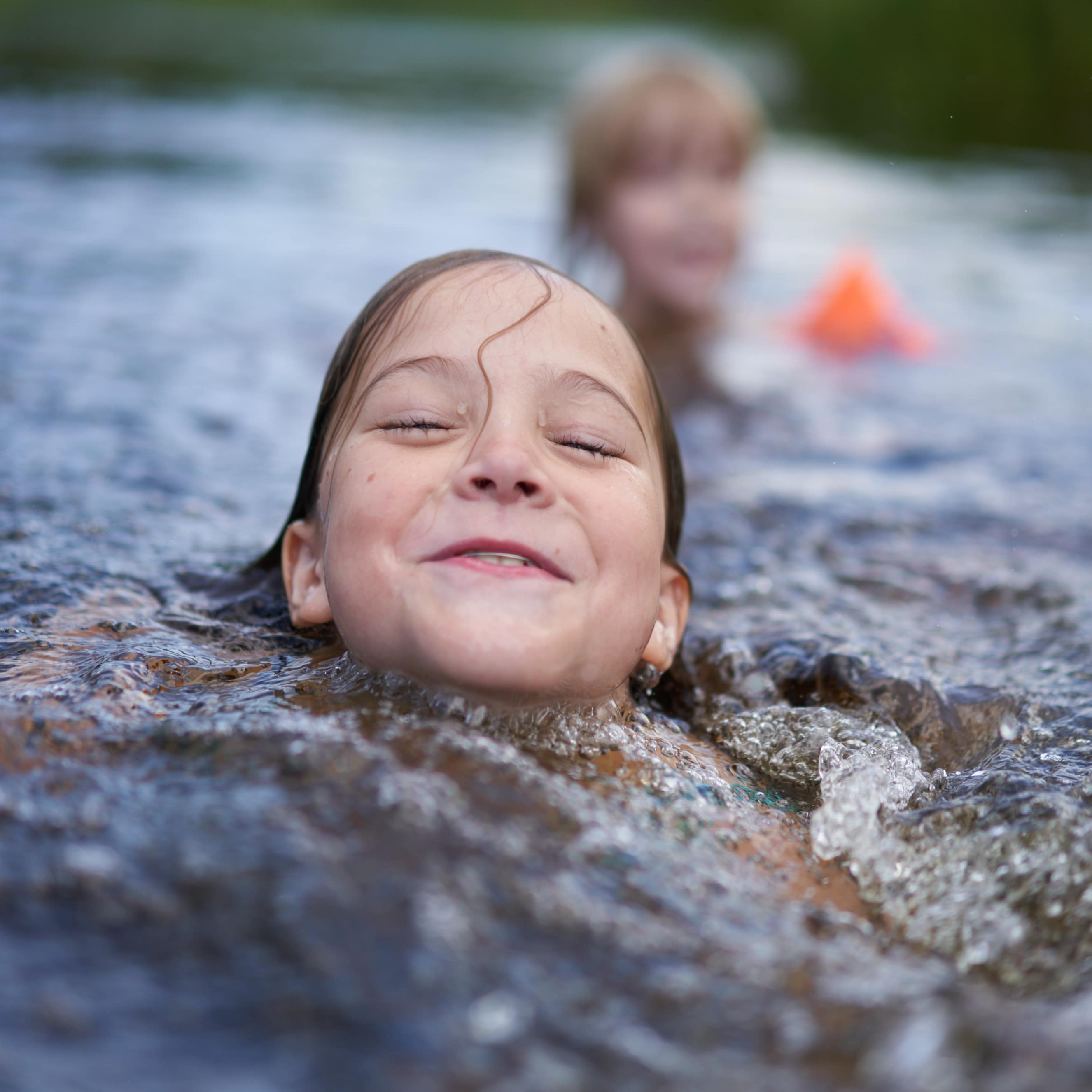 Girls swimming at the base of a waterfall