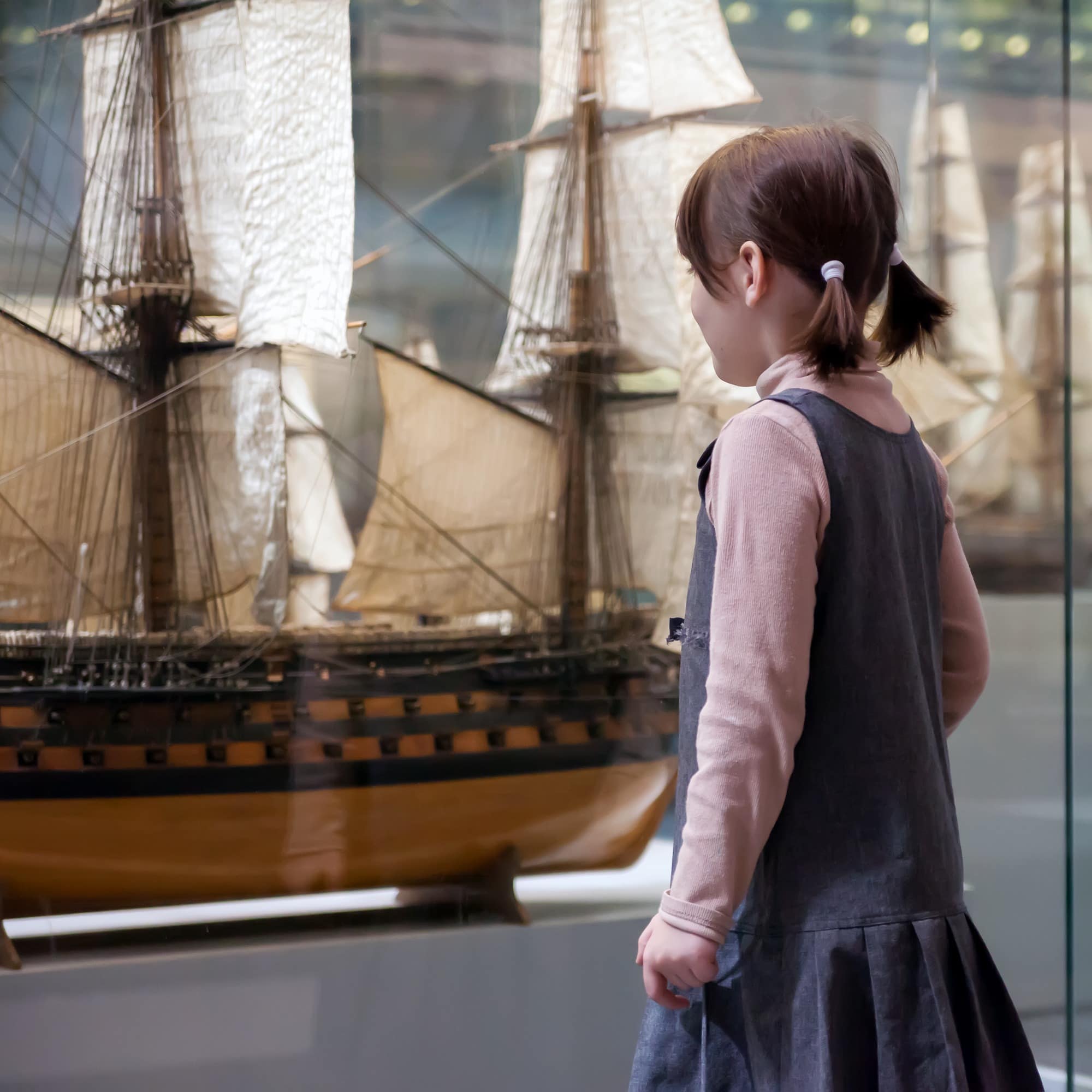 Girl looking at model ship in museum