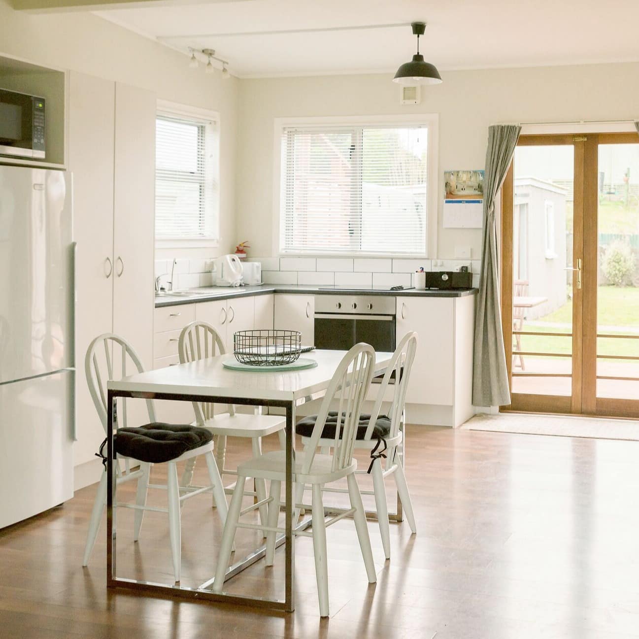 Interior of a modern beach bach, with a white-coloured kitchen and small table with chairs