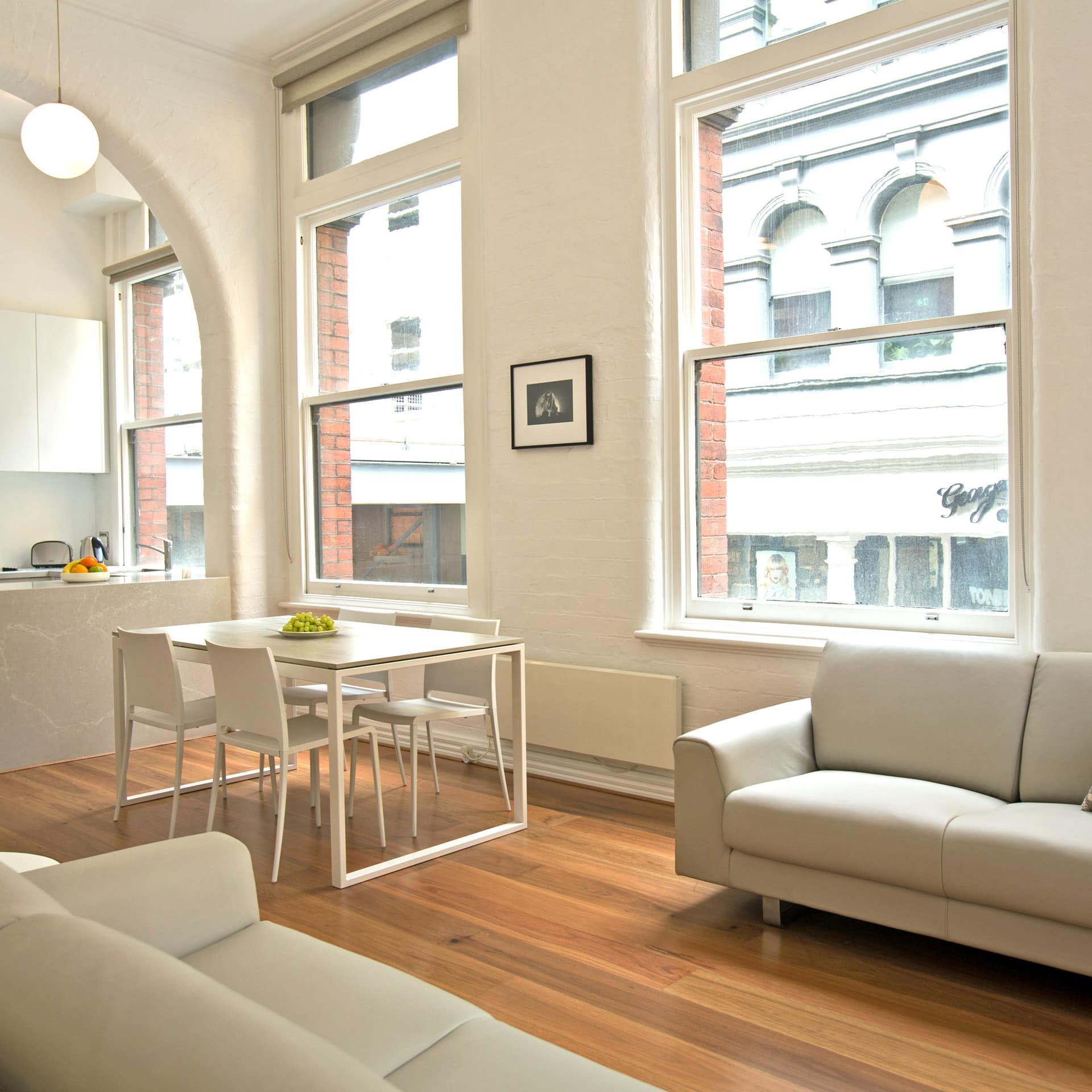 Open living, kitchen and dining areas of 1-bedroom apartment in historic building with large windows and lots of light
