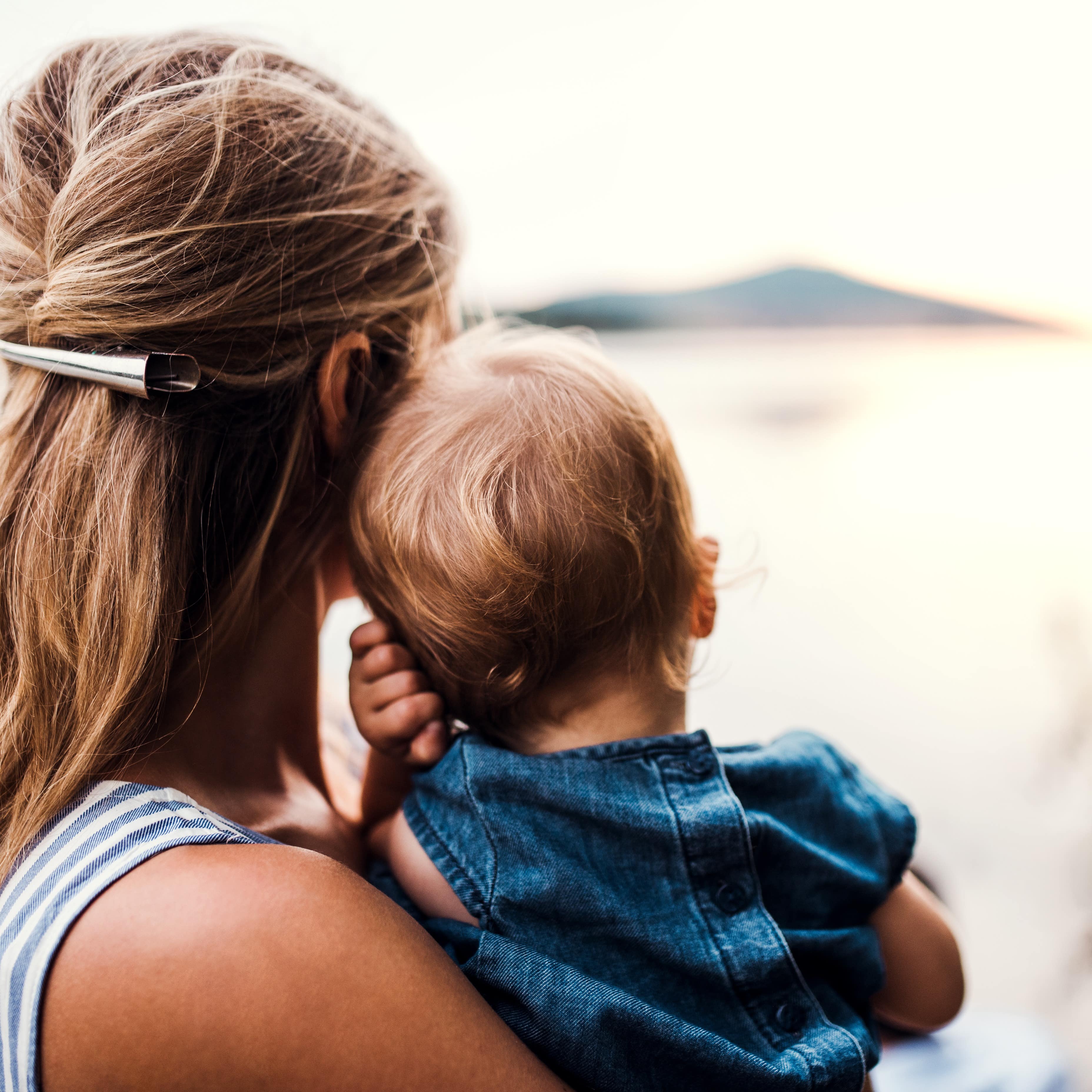 Mom holding child and looking at lake scenery