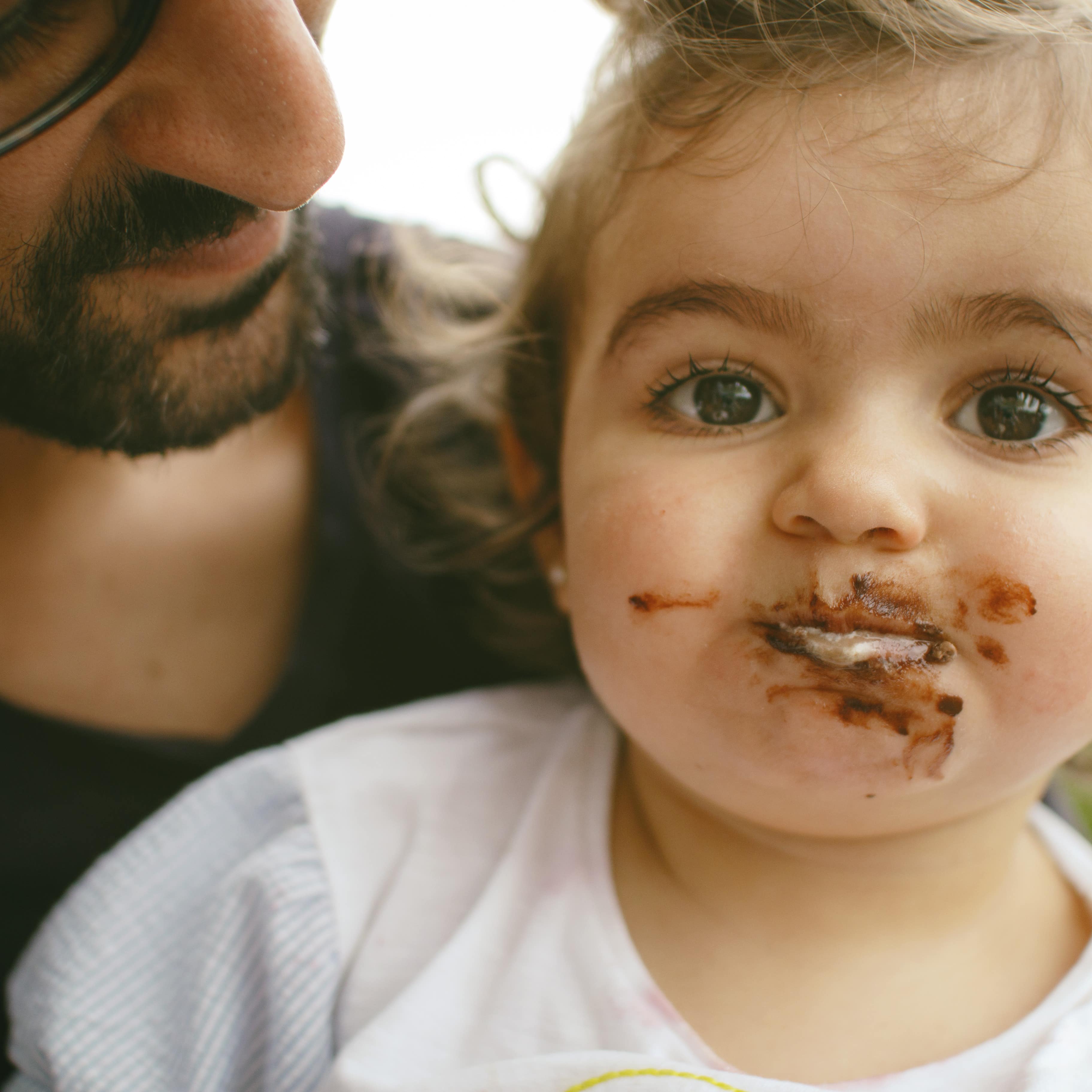 Father holding child whose mouth is covered in chocolate
