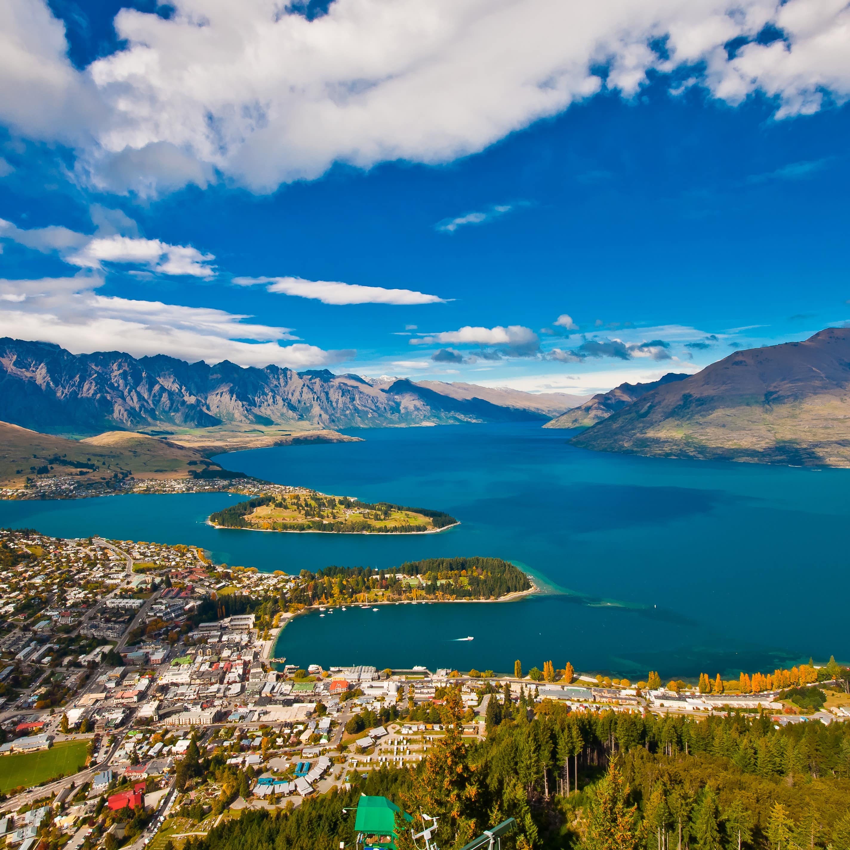 Aerial view of Queenstown with the city and neighbourhoods in the front and Lake Wakatipu and the Remarkables in the back