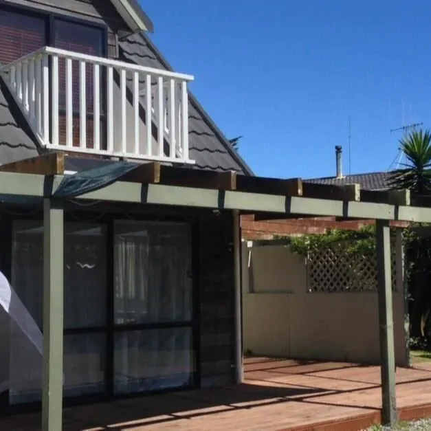 The outside of a holiday home in Otaki Beach with palm trees in the background