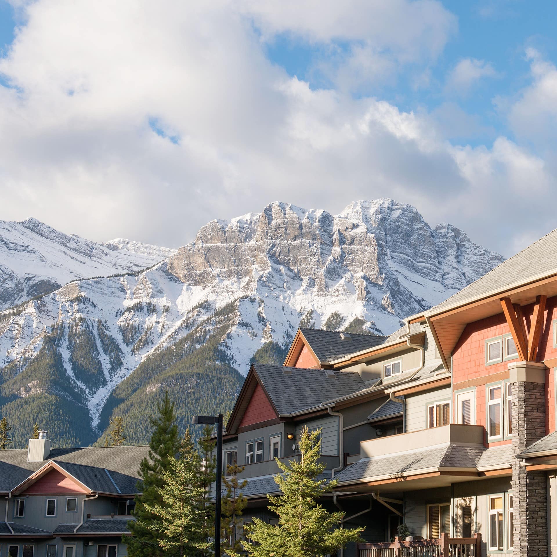 View of colourful condos in a resort town with snow-capped mountains in the background