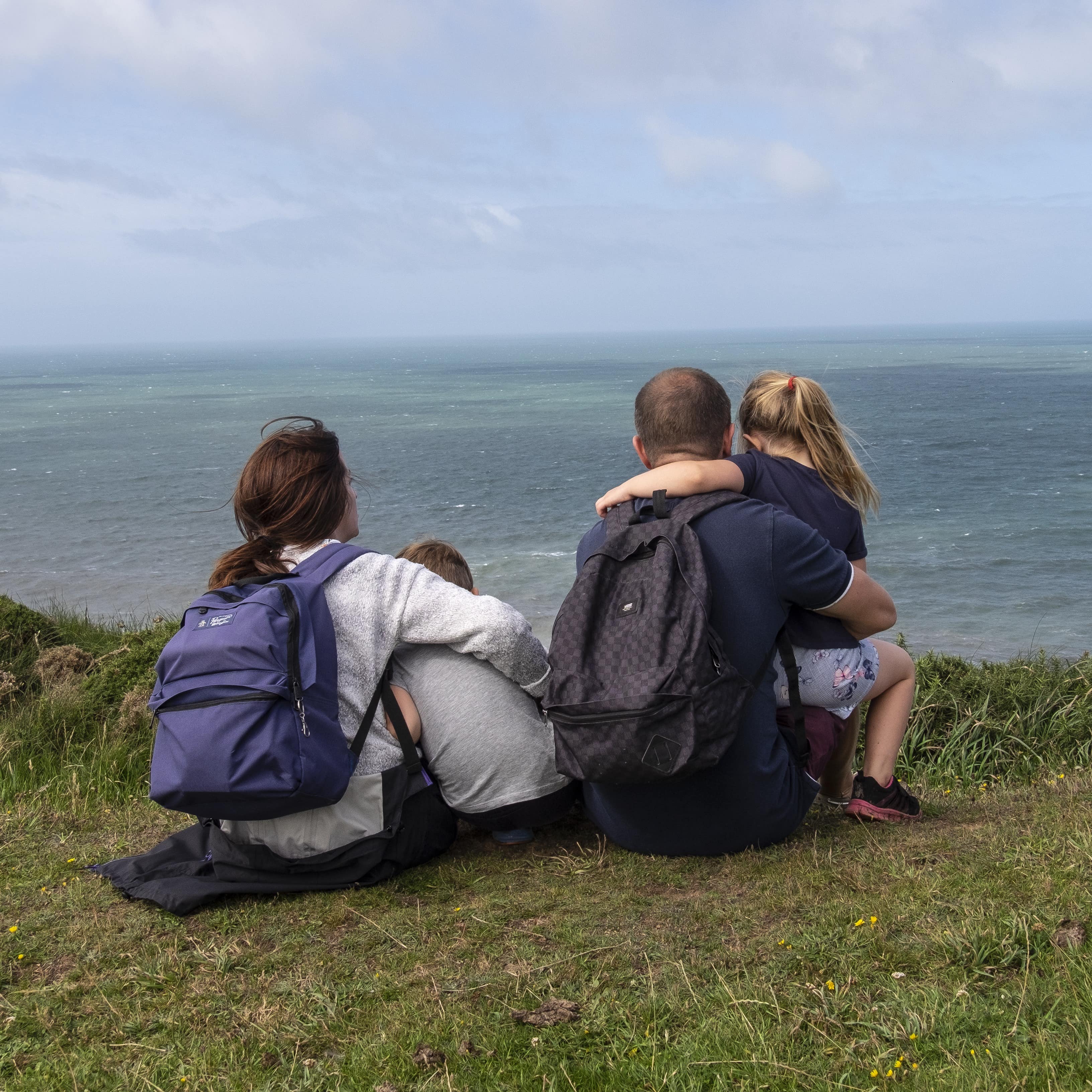 Family sitting on a grassy spot above the ocean