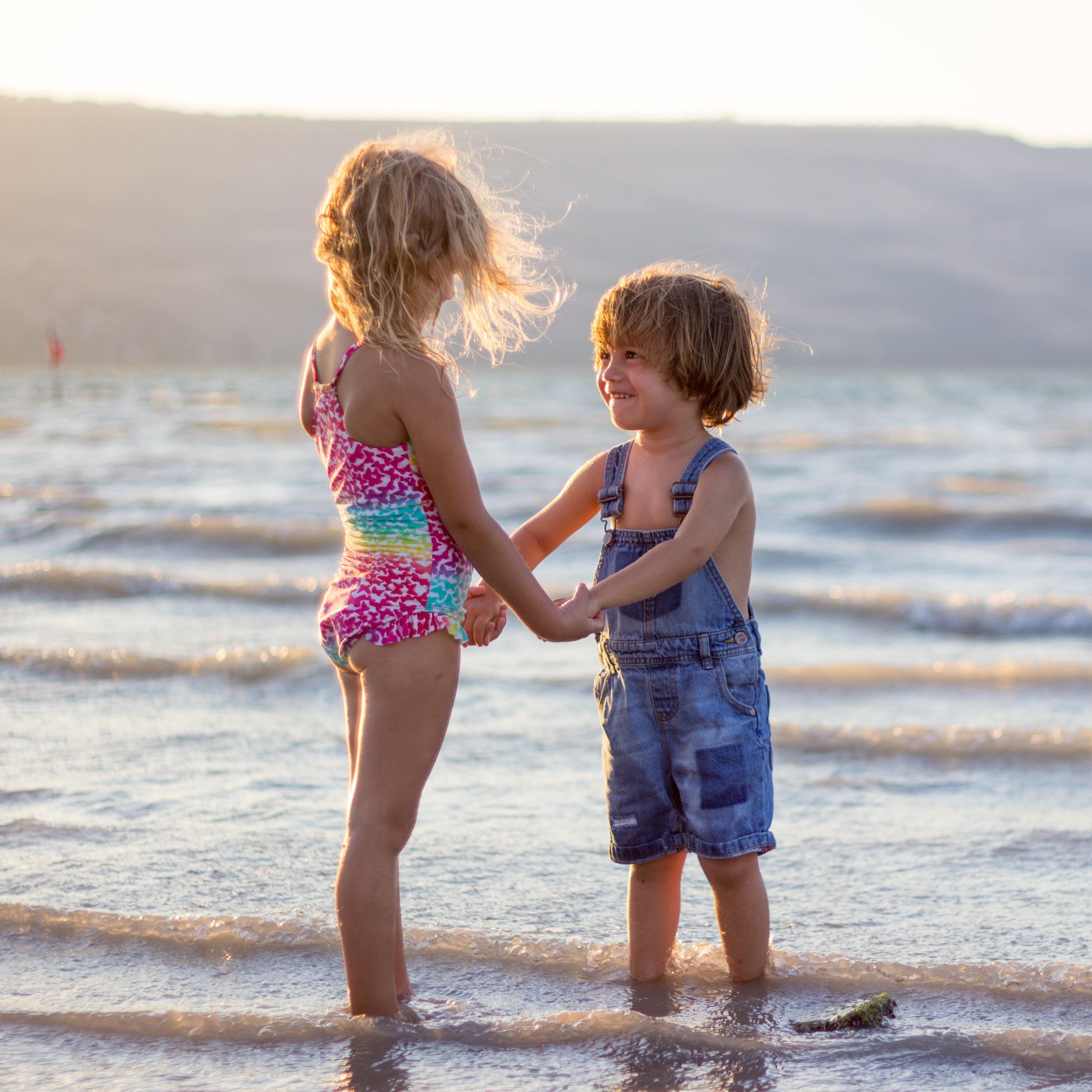 Little boy and girl holding hands in the water