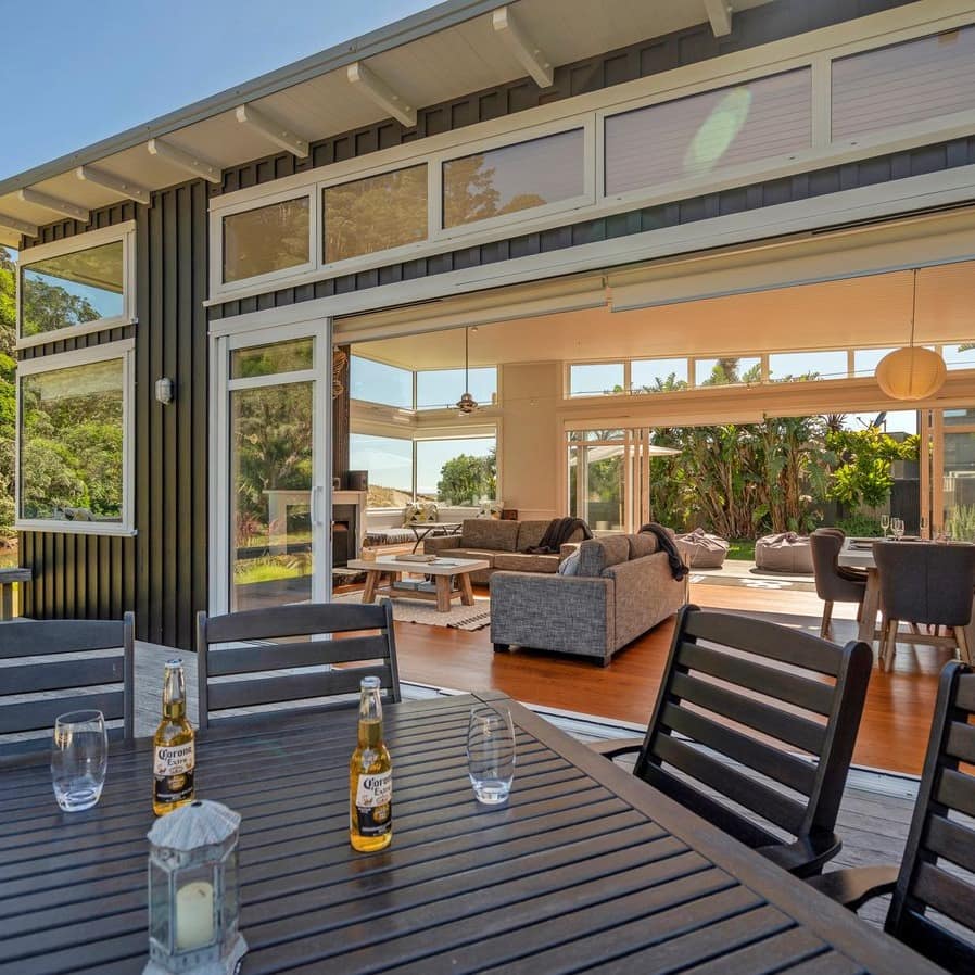 A contemporary, open holiday home with the outside deck set with two beers and glasses in the foreground