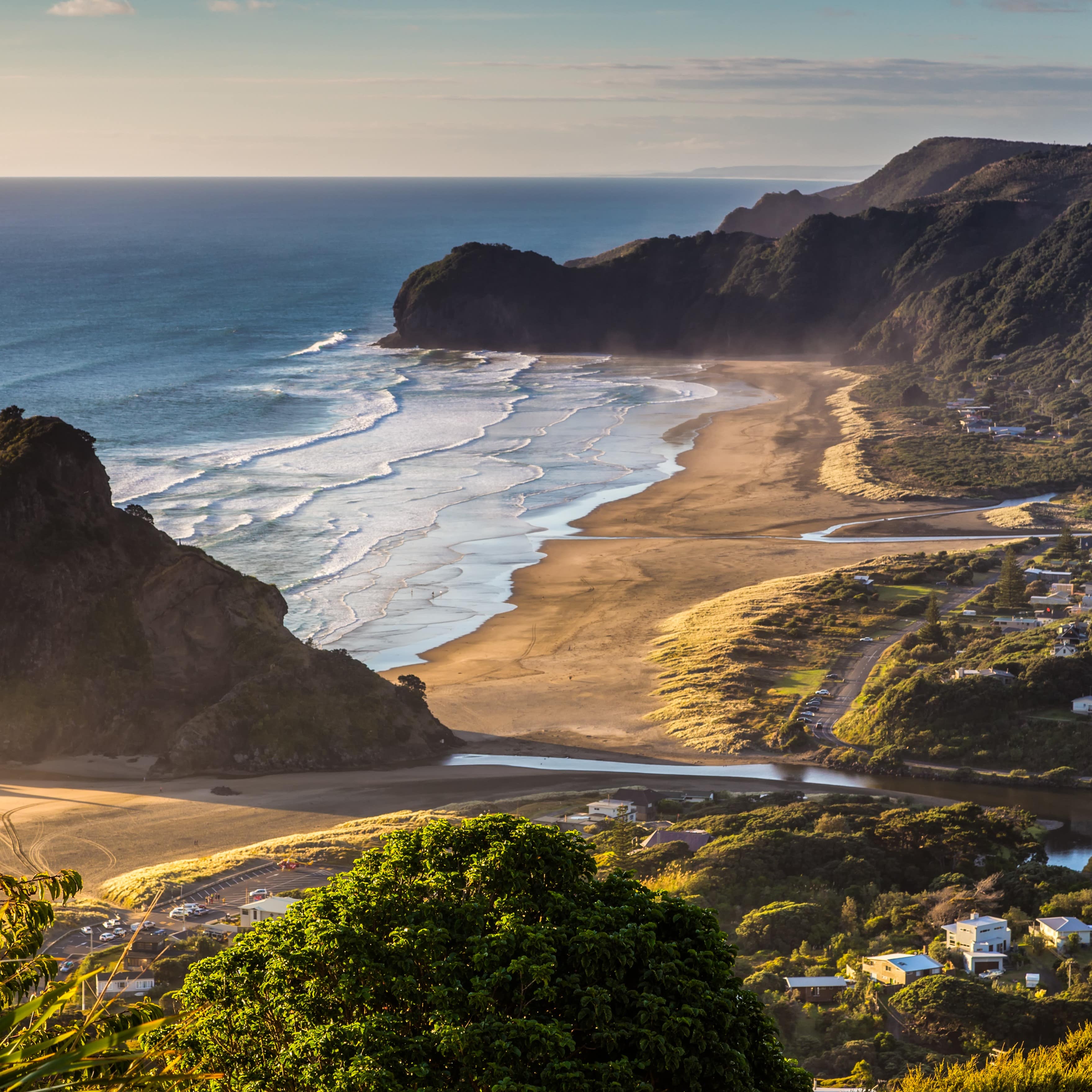 View looking down on New Zealand’s blue water, and cliff-lined beach