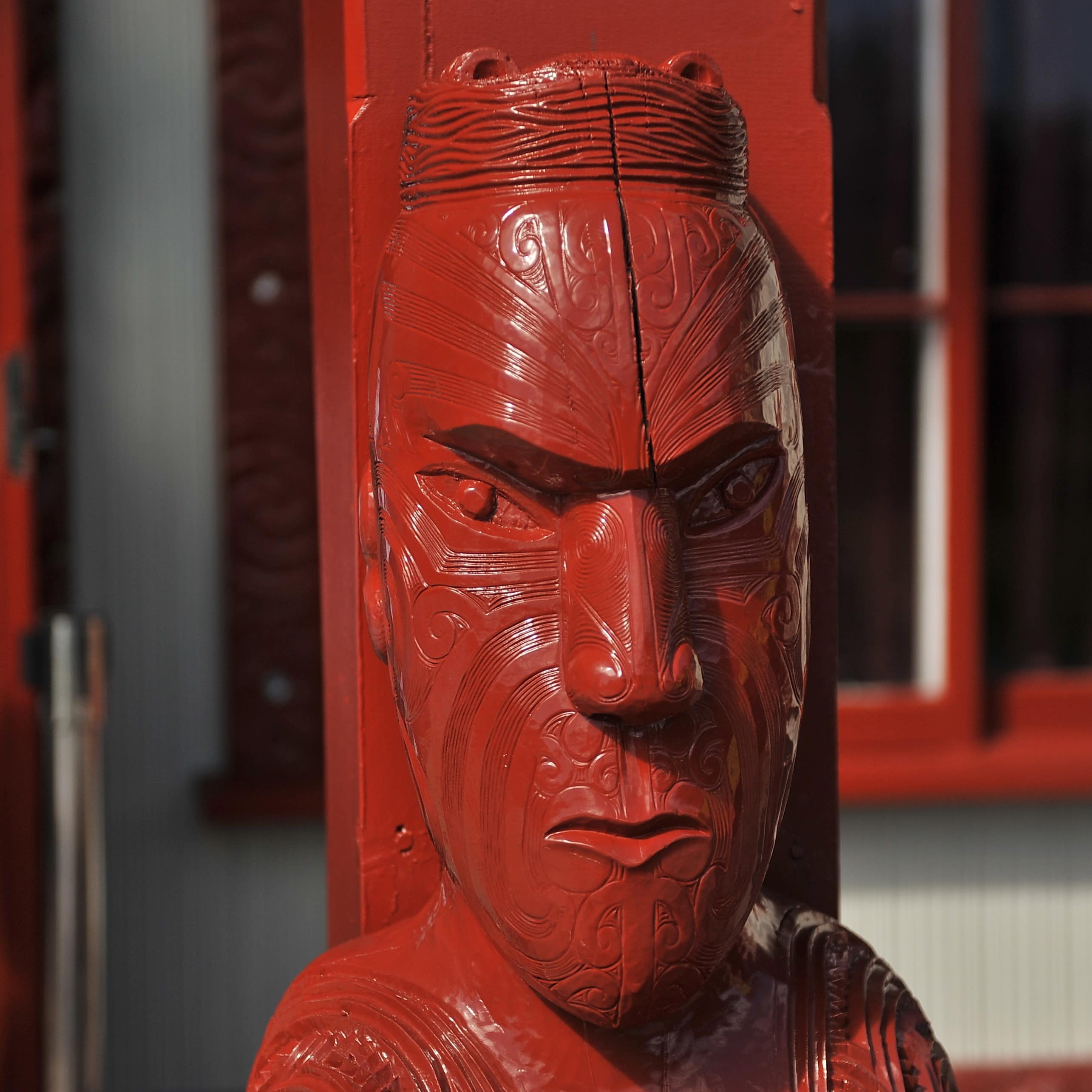 Red statue up close of face of Maori in museum in New Zealand