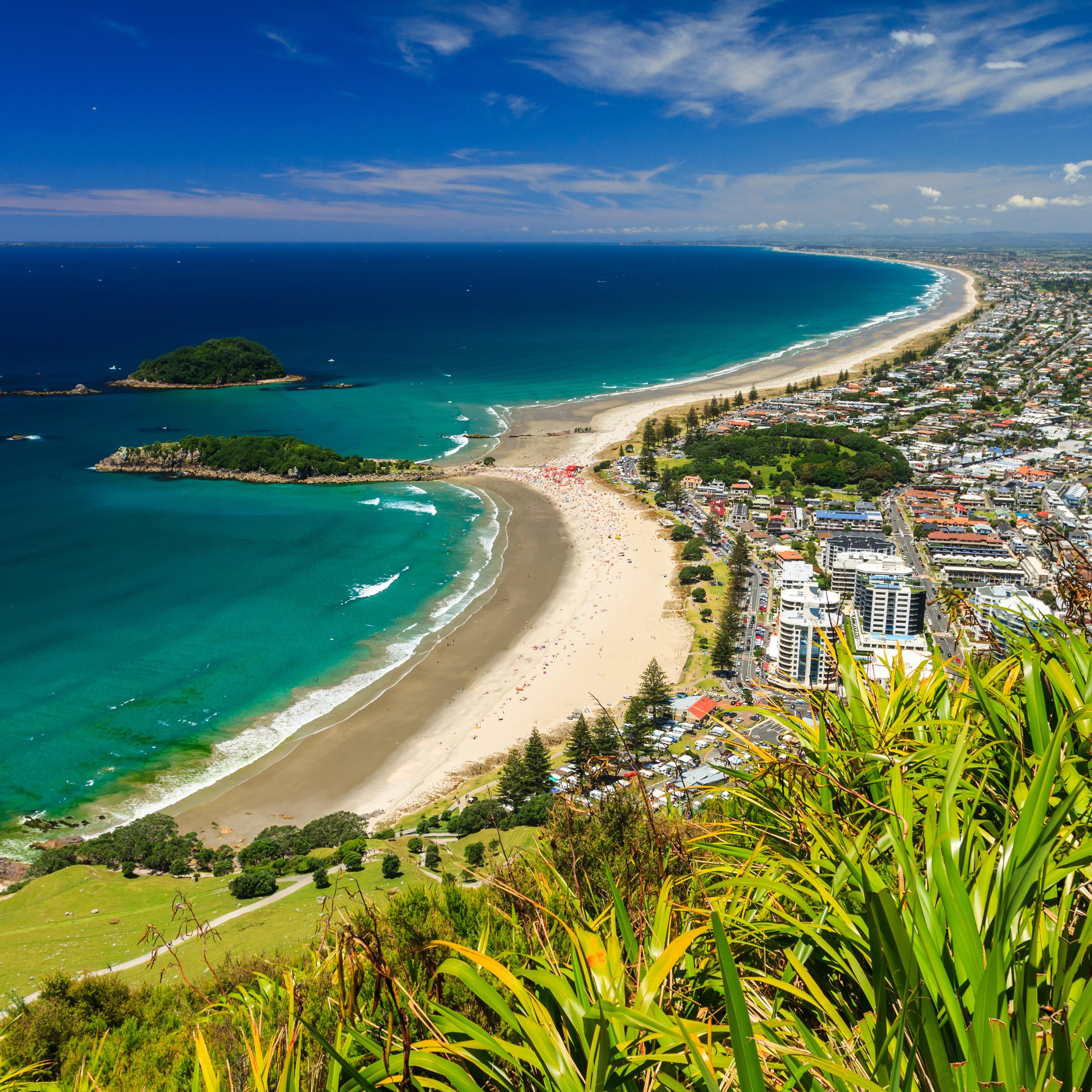 Aerial view of the bright blue ocean with the city of Tauranga on the right